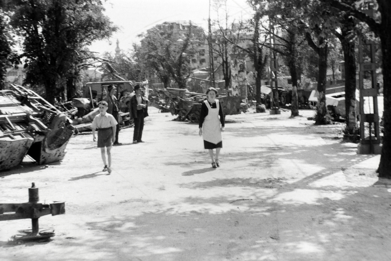 Magyarország, Budapest I., Vérmező a Déli pályaudvar felől a Krisztina tér felé nézve, jobbra a Krisztina körút házai., 1945, Fortepan, német gyártmány, életkép, járműroncs, harcjármű, Budapest, fasor, hölgy, járókelő, kötény, Fortepan #45585