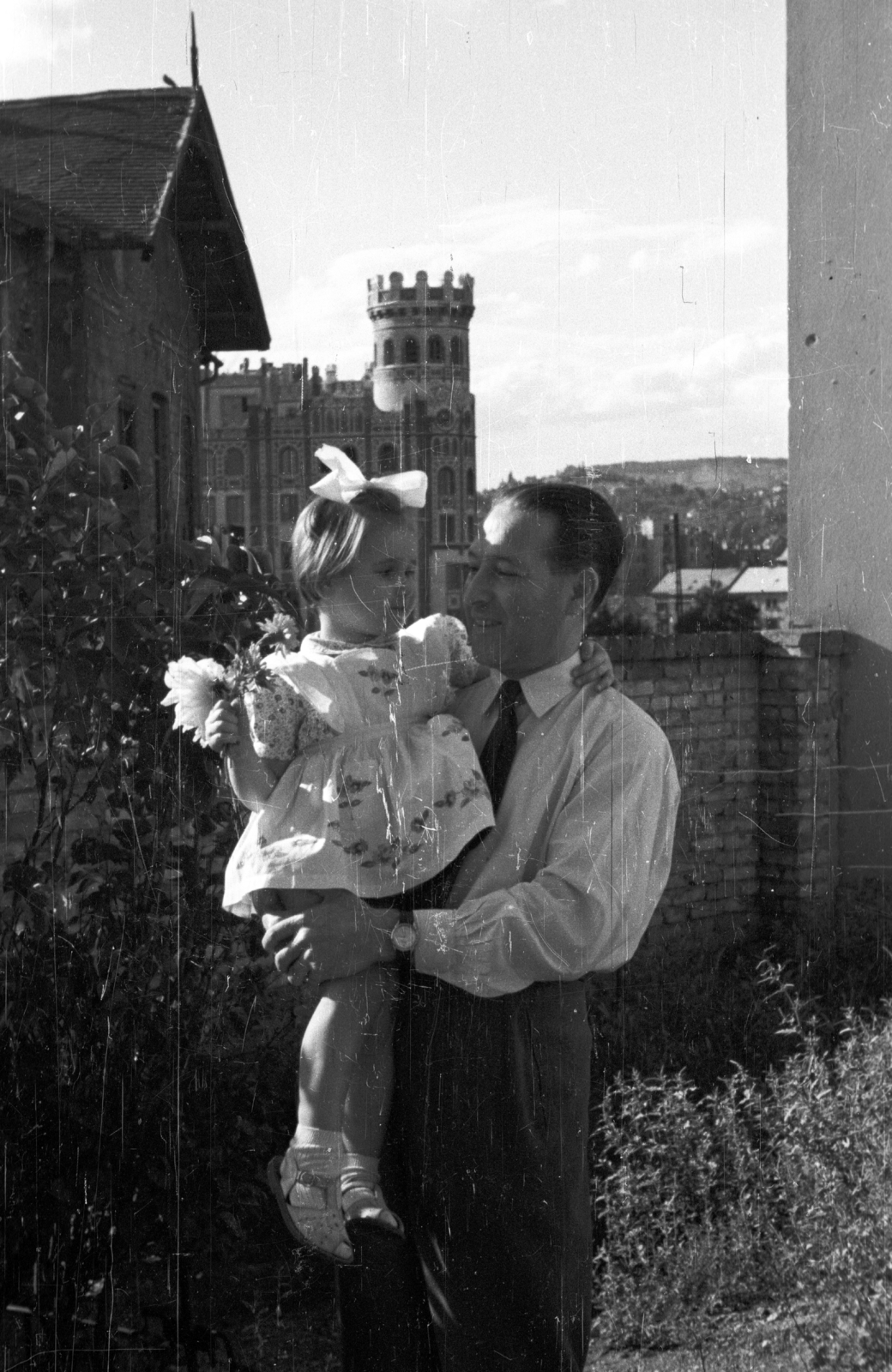 Magyarország, Budapest I., Mátray utca 9. számú ház kertje, háttérben a Krisztina körúti Postapalota., 1955, Krasznai Gyula, gyermek, kislány, virág, masni, Budapest, Fortepan #46018