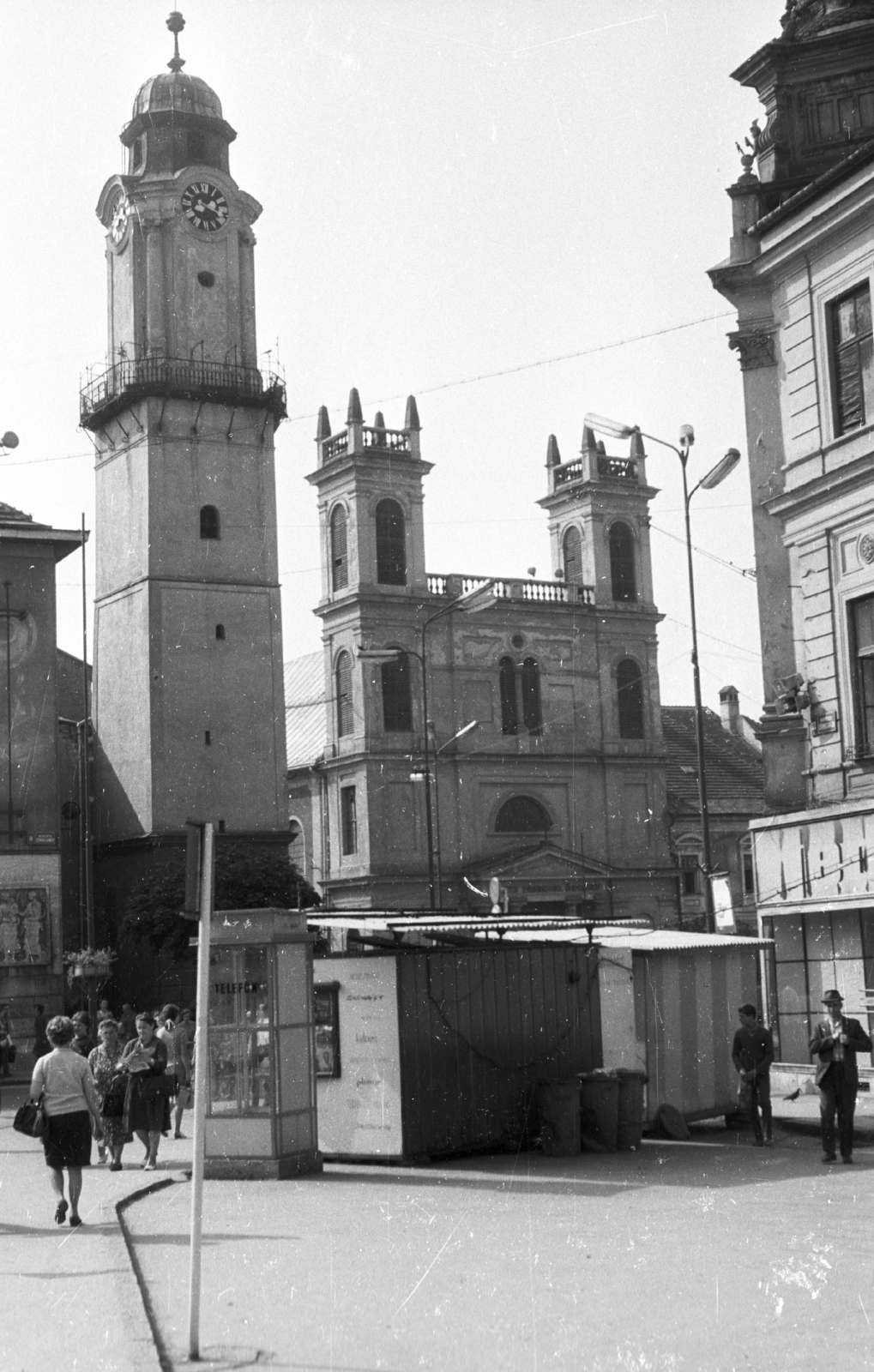 Slovakia, Banská Bystrica, szemben a Szlovák Nemzeti Felkelés (Slovenského národného povstania) terén (egykor IV. Béla király tér) az Óratorony és jobbra a Xavéri Szent Ferenc-székesegyház., 1969, Mészáros Zoltán, Czechoslovakia, church, watch, street view, genre painting, phone booth, lamp post, Upper Hungary, church clock, Cathedral, clock tower, Fortepan #46705