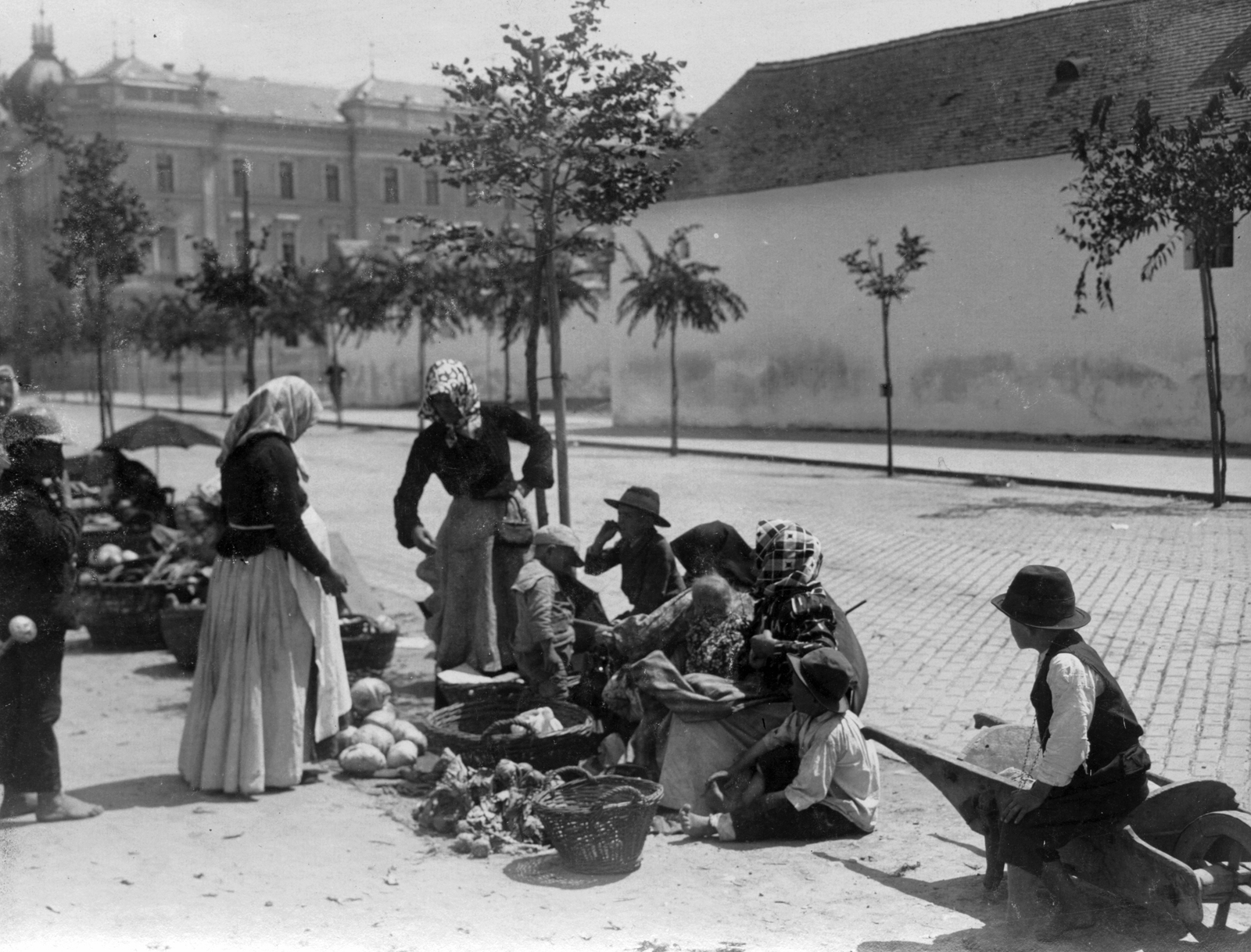 Hungary, Kecskemét, Rákóczi út, háttérben az Igazságügyi palota., 1907, Vargha Zsuzsa, hat, market, street view, waiting, display, umbrella, kids, basket, public building, wheelbarrow, headscarf, skirt, watering can, cabbage, haggling, Fortepan #47293