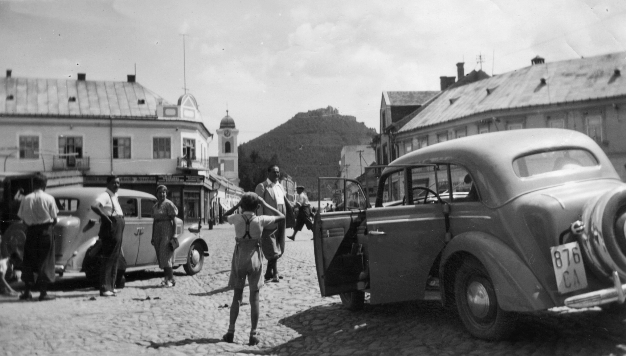 Ukraine,Zakarpattia Oblast, Khust, főtér, balra a Szent Anna-templom, háttérben a vár., 1940, Párdányi Miklós, German brand, Opel-brand, castle ruins, number plate, spare wheel, akimbo, Fortepan #47413