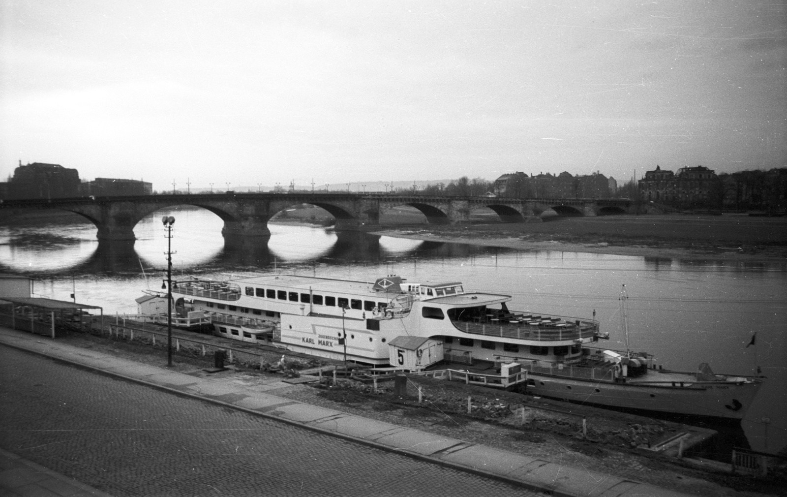 Germany, Dresden, az Augustusbrücke (Georgi-Dimitroff-Brücke) az Elba folyón. Az előtérben a Terassenufer, a Weisse Flotte kikötőjében a "Karl-Marx" dízelelektromos lapátkerekes hajó., 1965, Nagy Gyula, ship, bridge, picture, GDR, Karl Marx-ship, arch bridge, Fortepan #50446