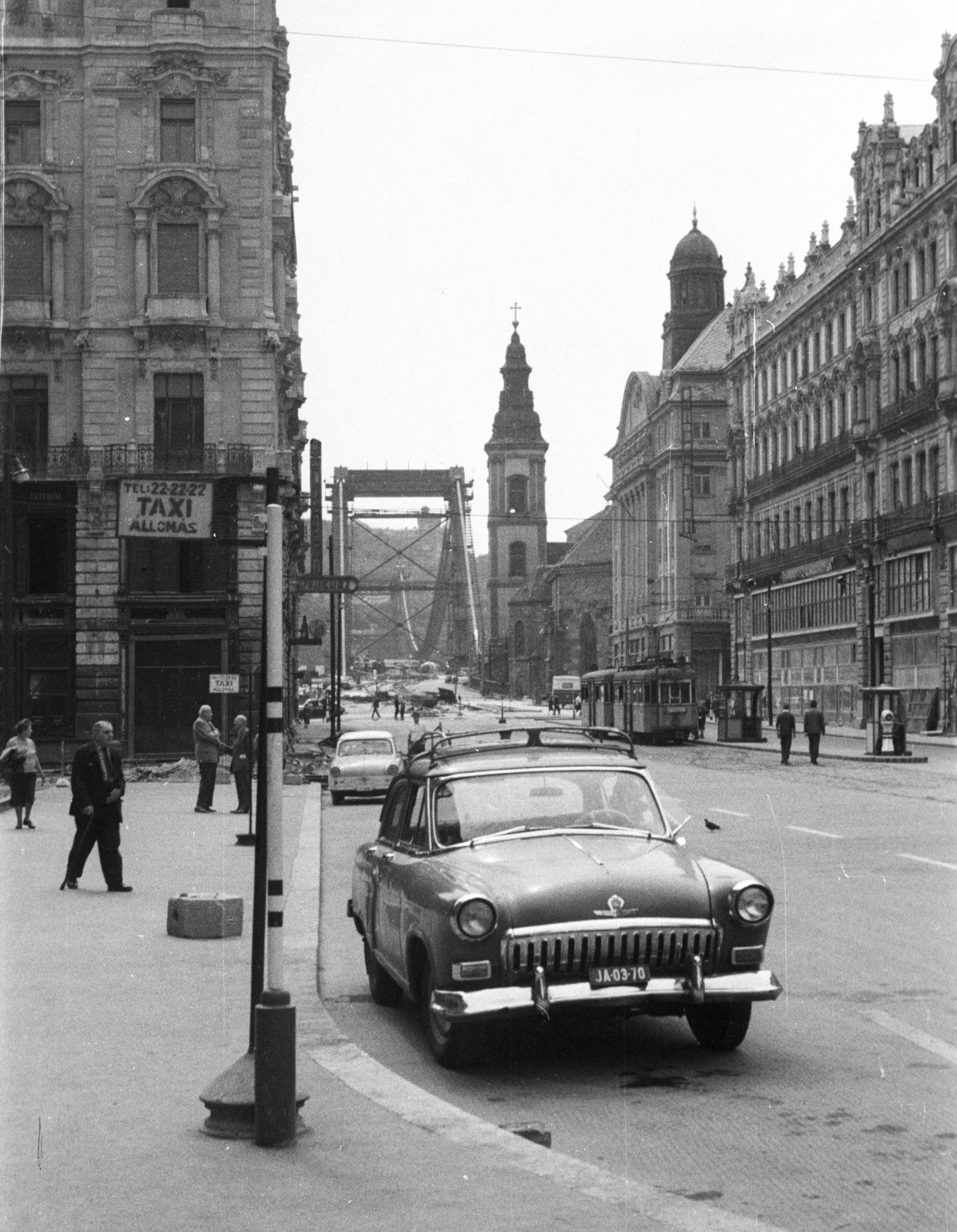 Magyarország, Budapest V., Ferenciek tere (Felszabadulás tér) a Szabad sajtó út felé nézve. Háttérben az épülő Erzsébet híd., 1964, Nagy Gyula, Trabant-márka, szovjet gyártmány, GAZ-márka, taxi, villamos, Korb Flóris-terv, Giergl Kálmán-terv, hídépítés, palota, villamosmegálló, GAZ M21 Volga, taxiállomás, eklektikus építészet, Budapest, Sávoly Pál-terv, Fortepan #50622