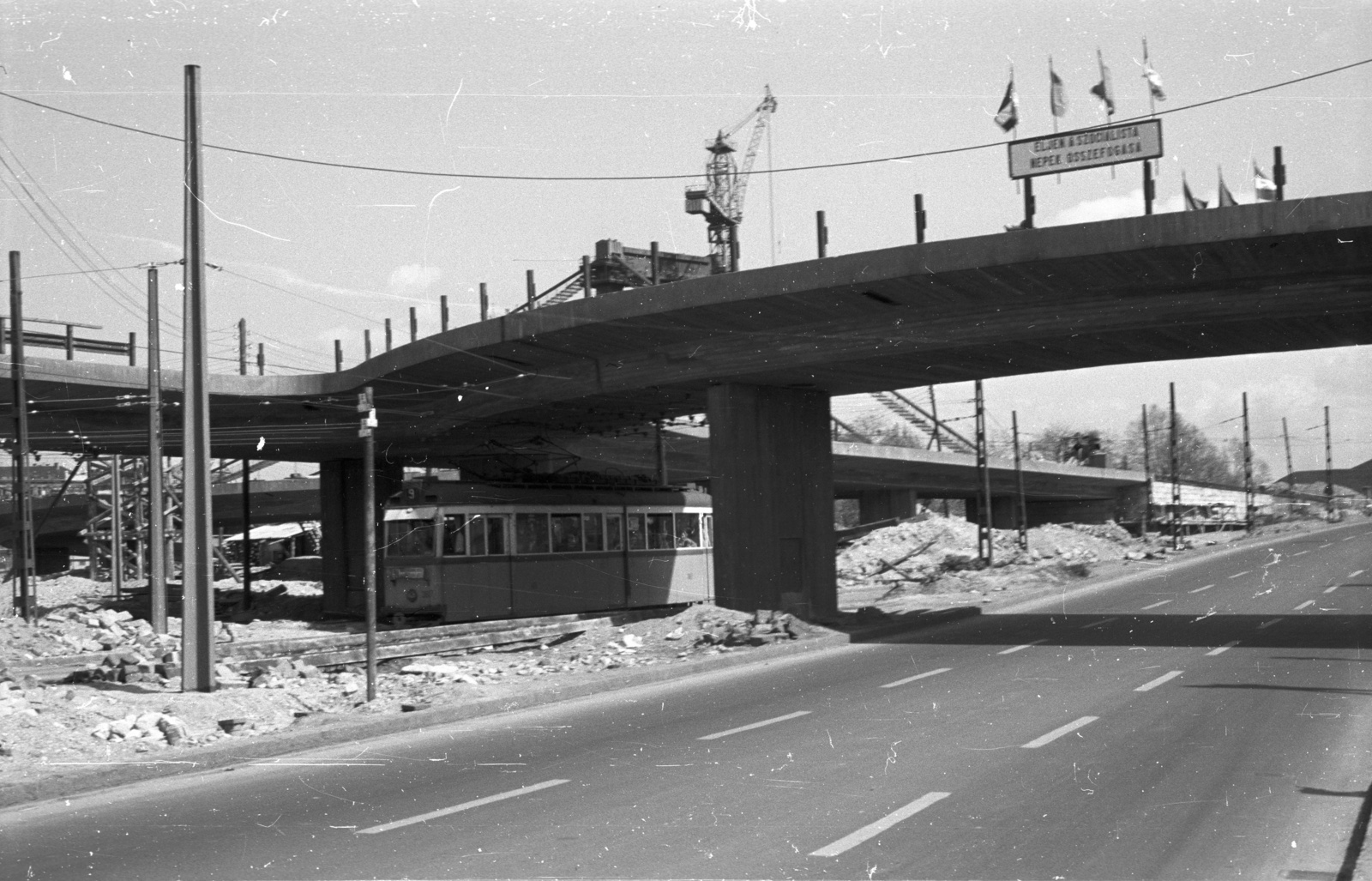 Hungary, Budapest I., Döbrentei tér, az Erzsébet híd épülő lejárója., 1964, Nagy Gyula, flag, construction, crane, tram, political decoration, Ganz-brand, Stuka tramway, Budapest, Fortepan #50736