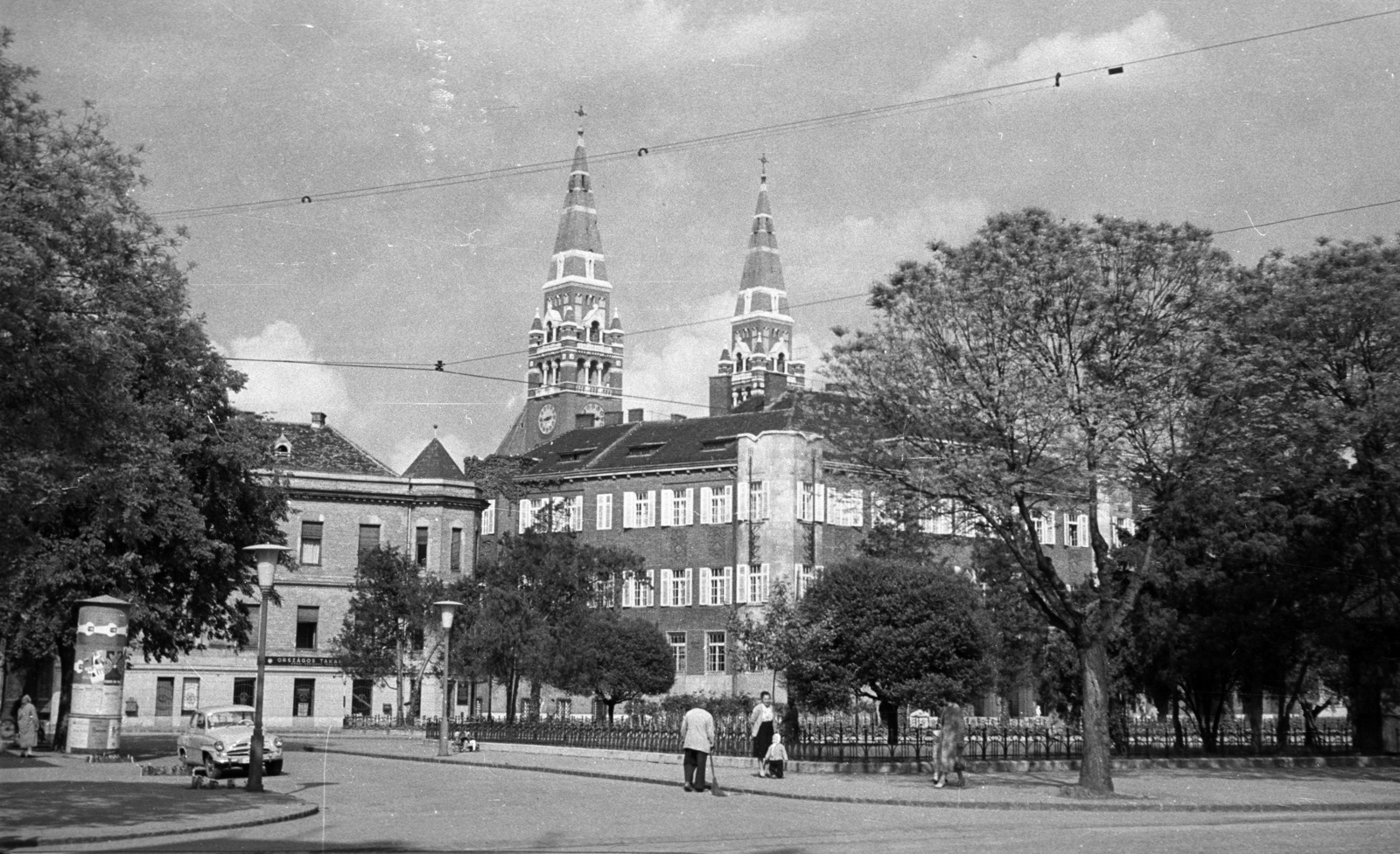 Hungary, Szeged, Tisza Lajos körút az Aradi vértanúk terénél. Szemben a Zrinyi utca és a Fogadalmi templom tornyai., 1961, Nagy Gyula, street view, genre painting, ad pillar, sweeper, lamp post, neon lights, Fortepan #51044