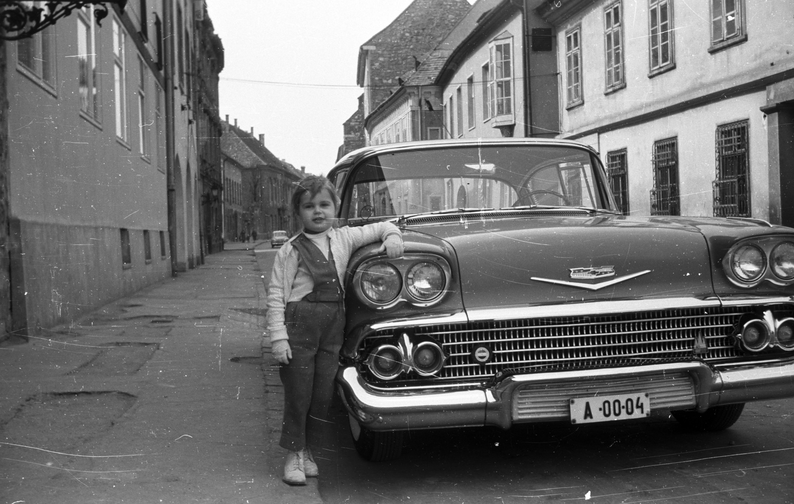 Hungary, Budapest I., Úri utca a Szentháromság utcától a Nőegylet utca felé nézve, Chevrolet típusú gépkocsi miniszteri rendszámmal (A)., 1959, Nagy Gyula, american brand, girl, Chevrolet-brand, automobile, number plate, Budapest, prop up on elbows, Fortepan #51233