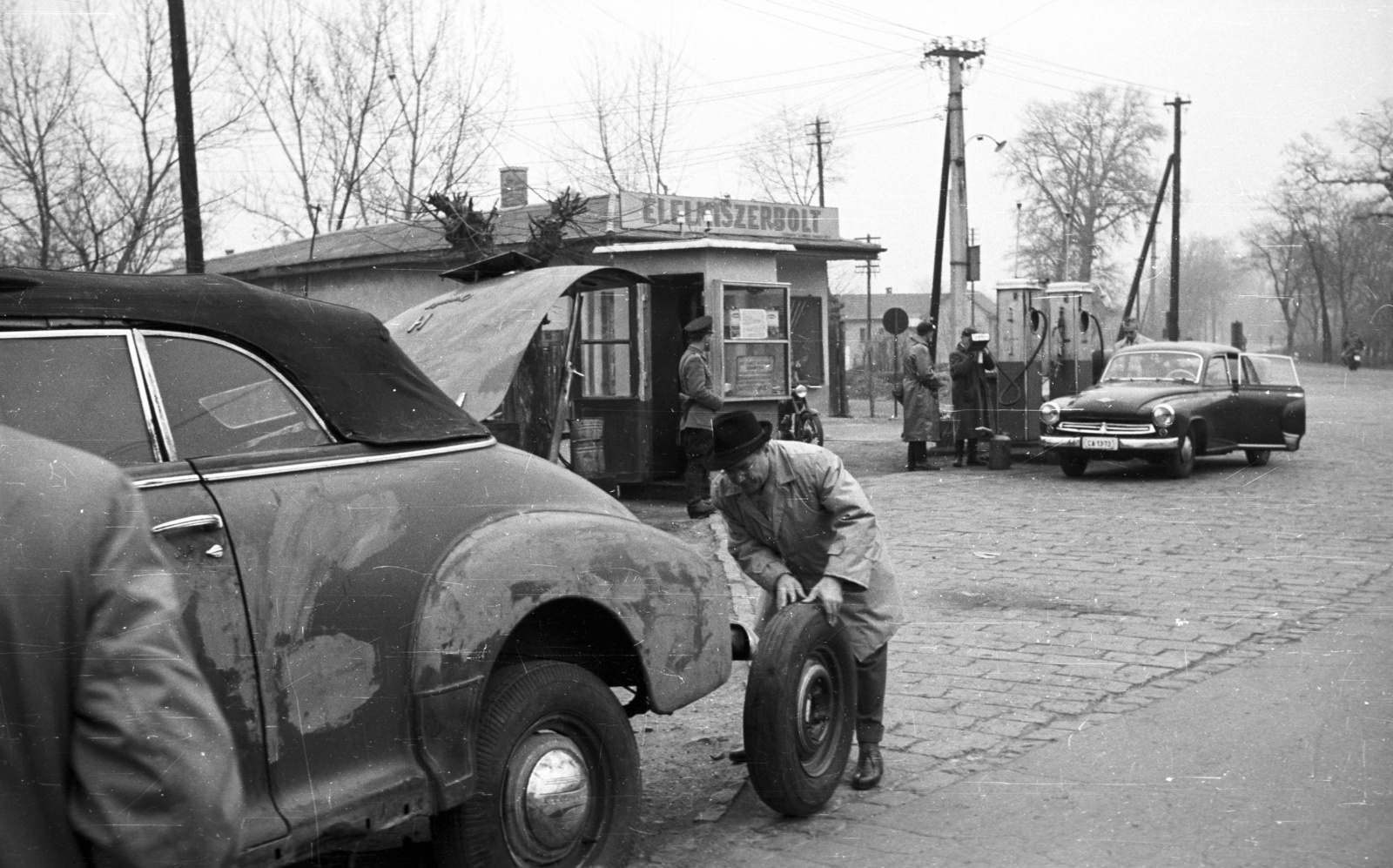 Hungary, Székesfehérvár, kerékcsere a Király sor (Élmunkás utca) - Budai út (Vöröshadsereg útja) - Seregélyesi út találkozásánál lévő benzinkút előtt., 1959, Nagy Gyula, Gerrman brand, Wartburg-brand, cop, gas station, Chevrolet-brand, cobblestones, spare wheel, Fortepan #51257