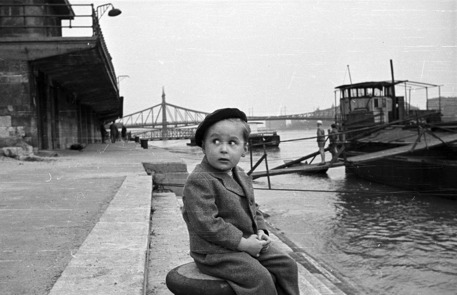 Hungary, Budapest V., Belgrád rakparti hajóállomás, háttérben a Szabadság híd., 1957, Nagy Gyula, barge, kid, shore, Danube, boat station, Budapest, Duna-bridge, János Feketeházy-design, grimace, beret, mooring bollard, Fortepan #51536