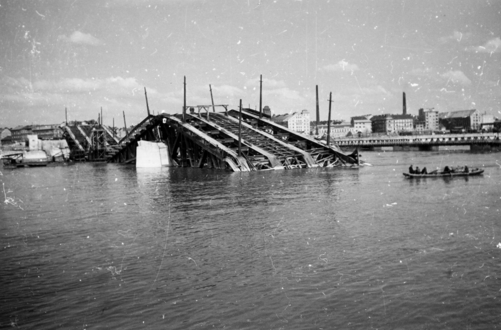 Magyarország, Budapest IX., Petőfi (Horthy Miklós) híd roncsai Budáról nézve. A pontonhíd mögött a Soroksári út épületei látszanak., 1945, Kramer István dr, Kunszt János, háborús kár, csónak, hídroncs, rom, Duna, gőzmalom, Budapest, Fortepan #52041