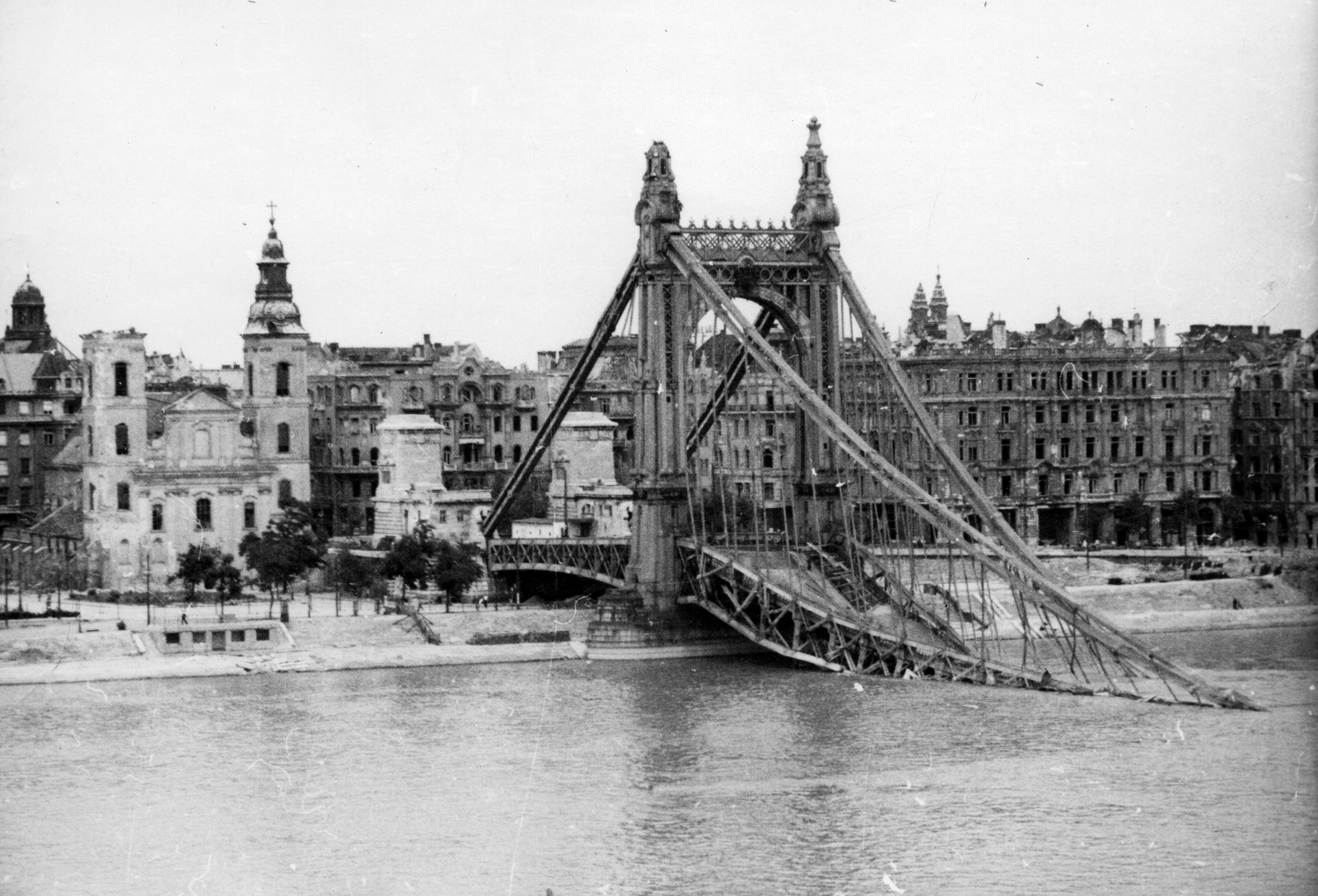 Magyarország, Budapest V., a lerombolt Erzsébet híd pesti hídfője a Duna felől nézve., 1945, Kramer István dr, Kunszt János, templom, háborús kár, hídroncs, rom, Duna, eklektikus építészet, Budapest, függőhíd, Duna-híd, Kherndl Antal-terv, Czekelius Aurél-terv, Fortepan #52044