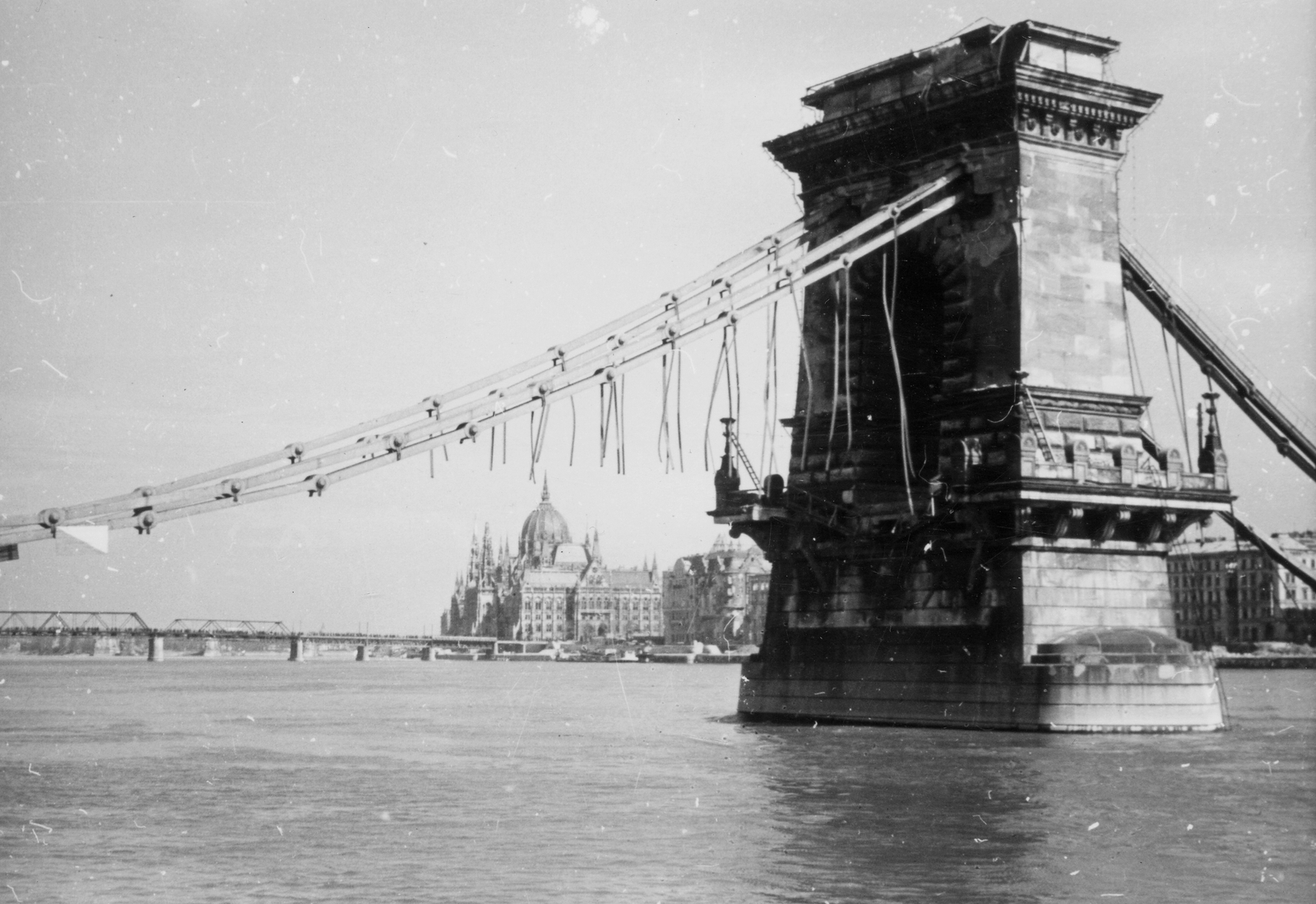 Magyarország, Budapest V., a lerombolt Széchenyi Lánchíd, háttérben a Parlament és a Kossuth híd., 1946, Kramer István dr, Kunszt János, Kossuth híd, híd, háborús kár, hídpillér, hídroncs, Steindl Imre-terv, neogótika, Duna, eklektikus építészet, Budapest, függőhíd, William Tierney Clark-terv, Fortepan #52060