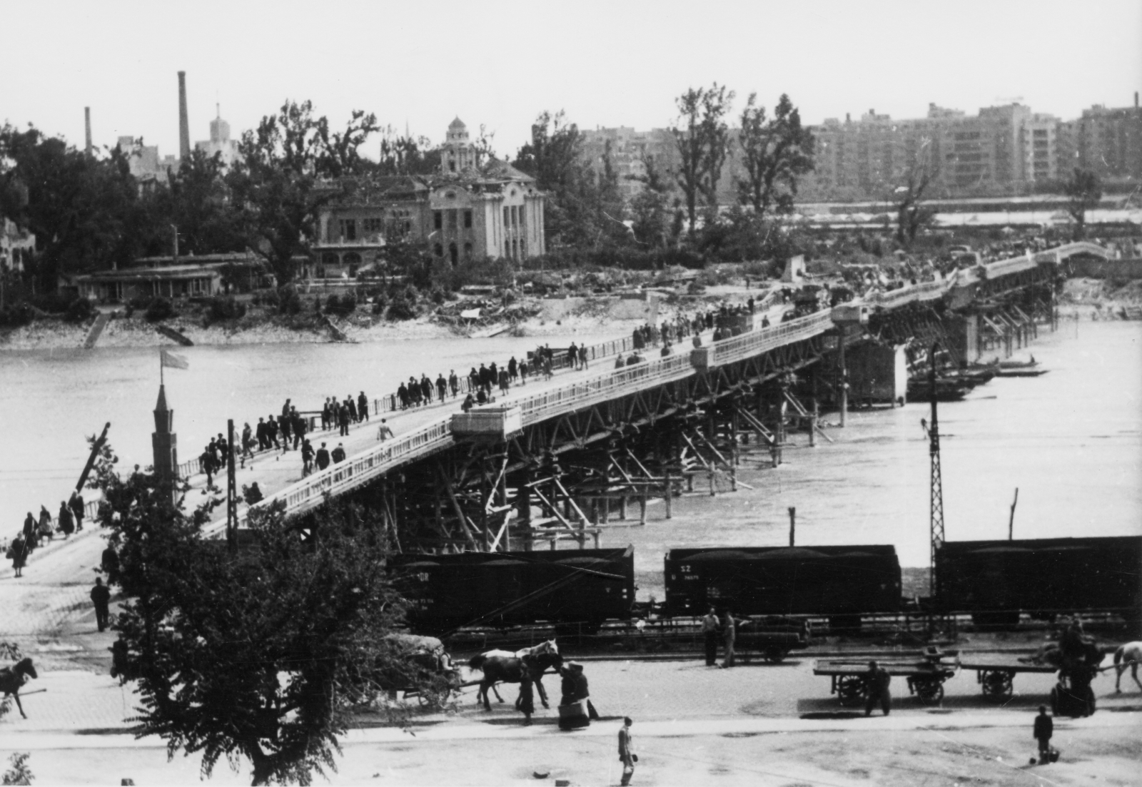 Hungary, Budapest II., a hadi hídként épült Manci híd Árpád fejedelem útja és Margitsziget közötti szakasza. A szigeten a Magyar Athlétikai Club klubháza., 1945, Kramer István dr, Kunszt János, railway, bridge, river, chariot, Horse-drawn carriage, water surface, pedestrian, genre painting, coach, shore, coach, Budapest, temporary bridge, Fortepan #52105