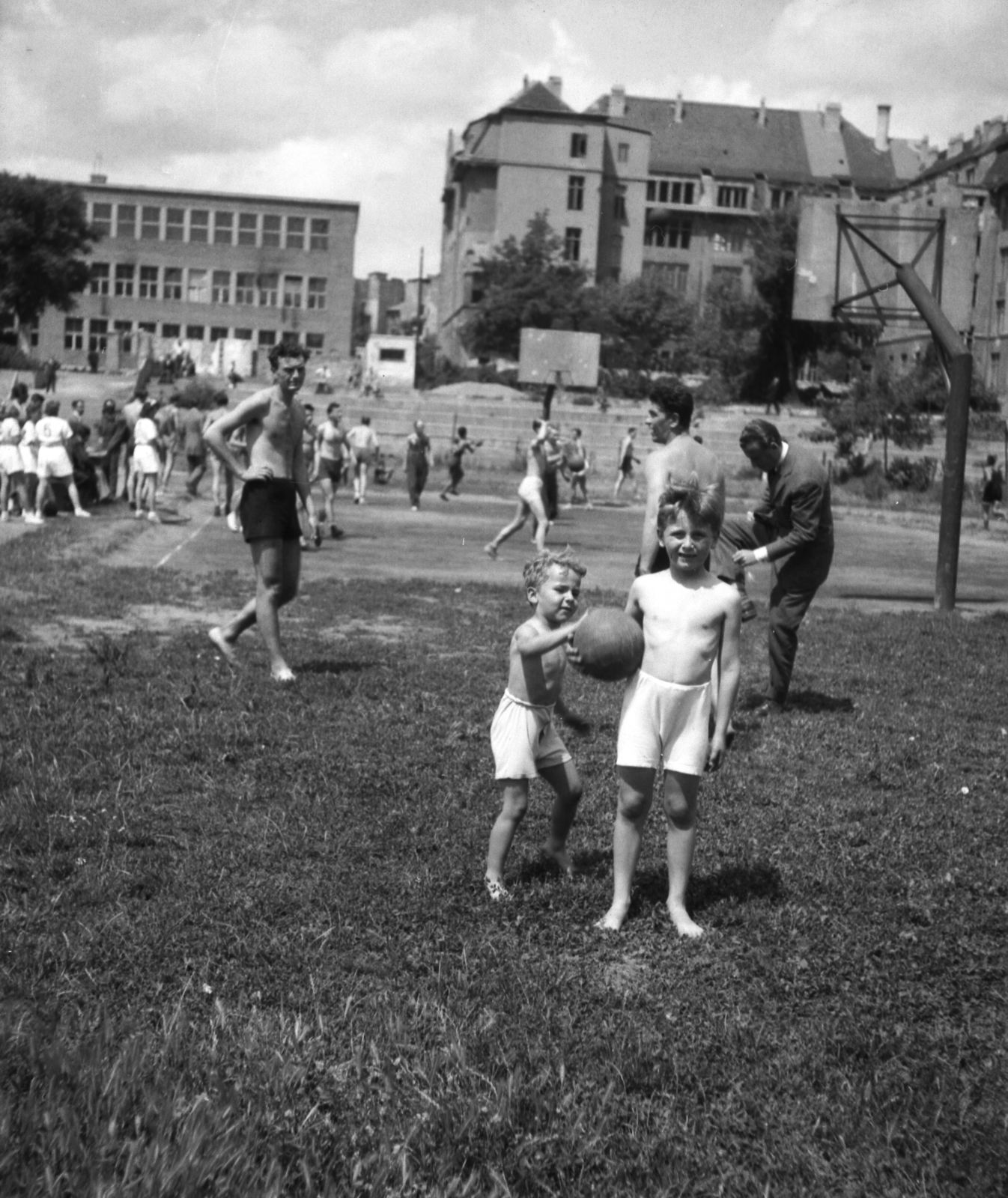 Magyarország, Budapest XI., Kőrösy József (Mező) utca, BEAC-pálya. Háttérben a Váli utcai iskola (később József Attila Gimnázium) és a Közgazdasági Technikum (később Fényes Elek Közgazdasági Szakközépiskola)., 1959, Fortepan, Budapest, félmeztelen, Fortepan #52874