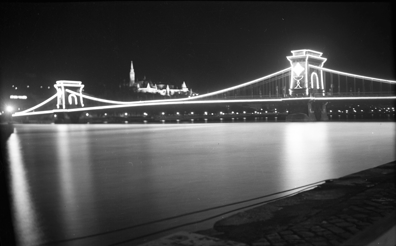 Magyarország, Budapest V.,Budapest I., kilátás a pesti alsó rakpartról, a Széchenyi Lánchíd felett a Halászbástya és Mátyás-templom. Díszkivilágítás az Eucharisztikus Világkongresszus alkalmával., 1938, Romák Éva, Duna, díszkivilágítás, Budapest, függőhíd, William Tierney Clark-terv, Fortepan #53217