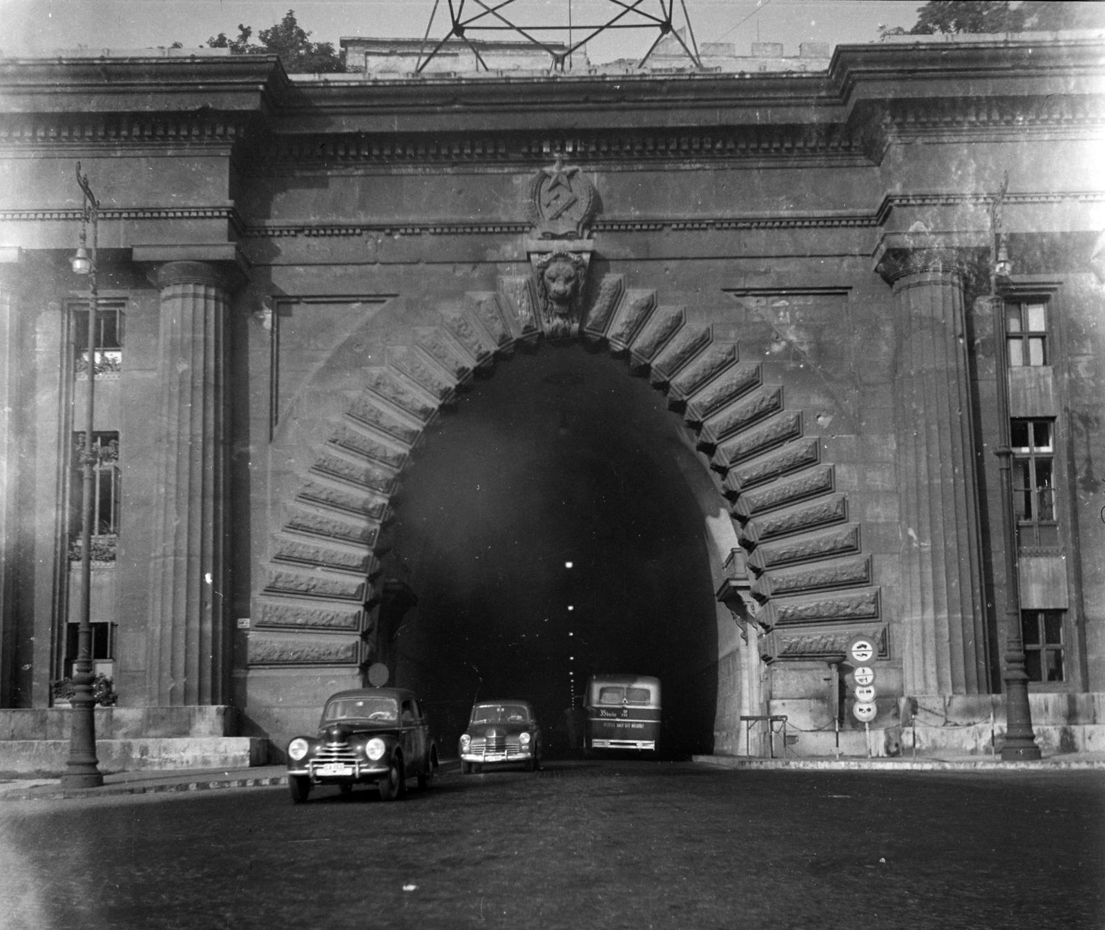 Magyarország, Budapest I., Clark Ádám tér, az Alagút bejárata., 1954, UVATERV, forgalom, autóbusz, csehszlovák gyártmány, utcakép, életkép, Skoda-márka, MÁVAG-márka, alagút, lámpaoszlop, címer, automobil, Skoda 1101/1102 Tudor, MÁVAG Tr5, Budapest, Rákosi-címer, Fortepan #5336