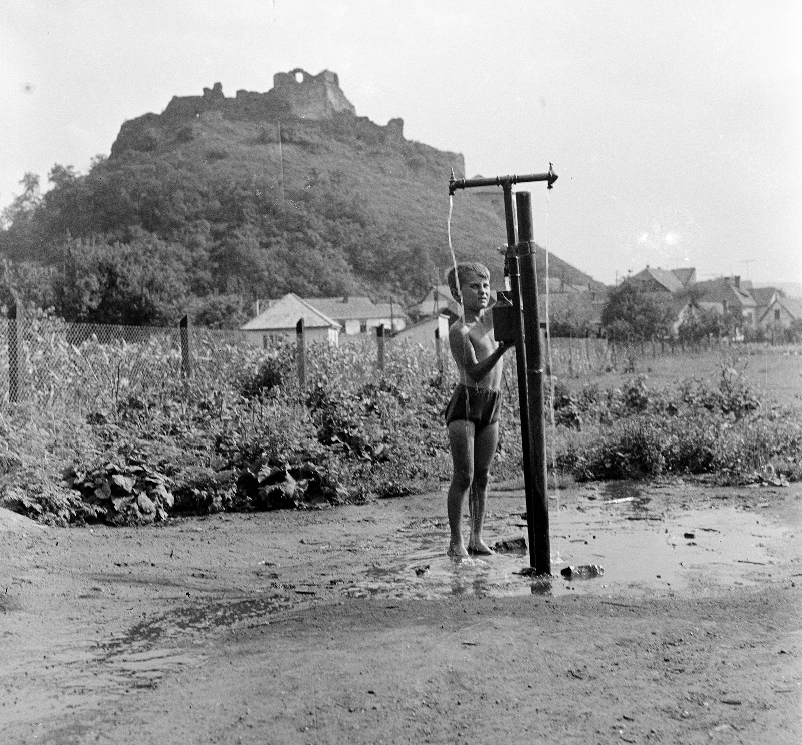 Slovakia, Fiľakovo, Farská lúka (Paprét), az egyik "csevice" forrás, háttérben a vár., 1959, Zsanda Zsolt, Vajszada Károly, Czechoslovakia, well, castle ruins, barefoot, Fortepan #53792