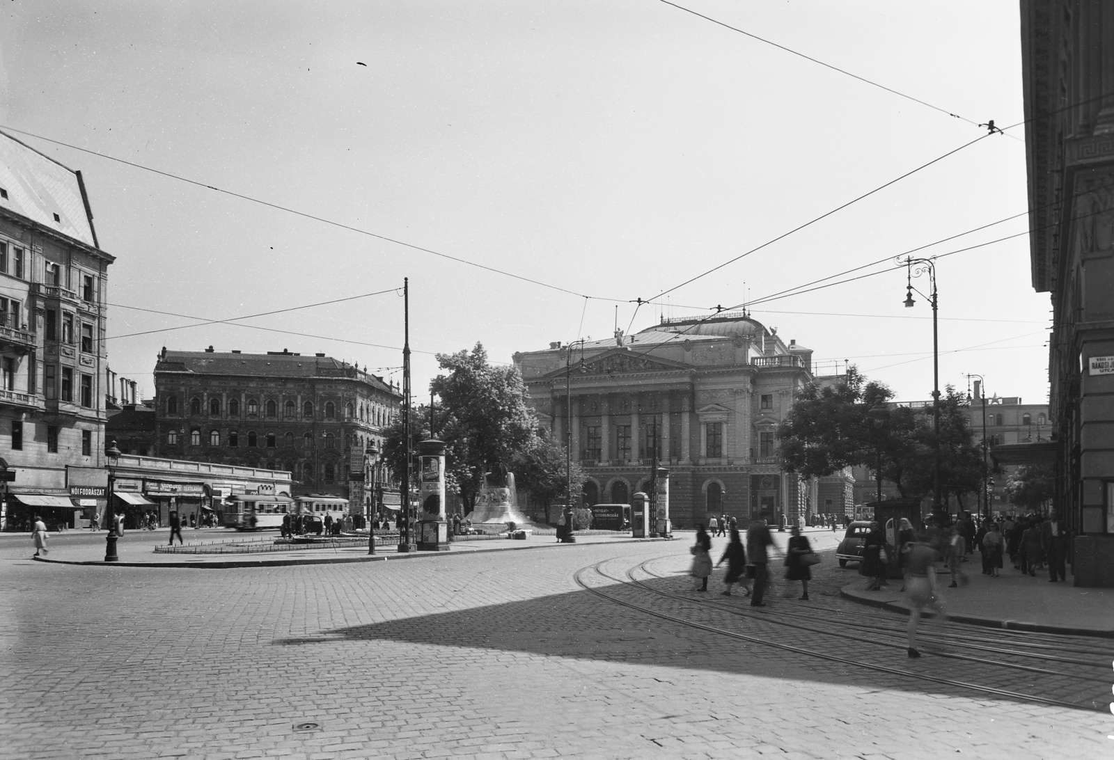 Hungary, Budapest VIII., Blaha Lujza tér a Márkus Emilia (Rákosi Jenő) utcától nézve. Szemben a Nemzeti Színház, előtte Tinódi Lantos Sebestyén szobra (Bezerédi Gyula, 1907.), jobbra a Corvin Áruház., 1951, UVATERV, street furniture, national theater, monument, Fellner and Helmer-design, lamp post, number plate, Patyolat shop, eclectic architecture, Budapest, Sebestyén Tinódi Lantos-portrayal, Gyula Bezerédi-design, Fortepan #5385