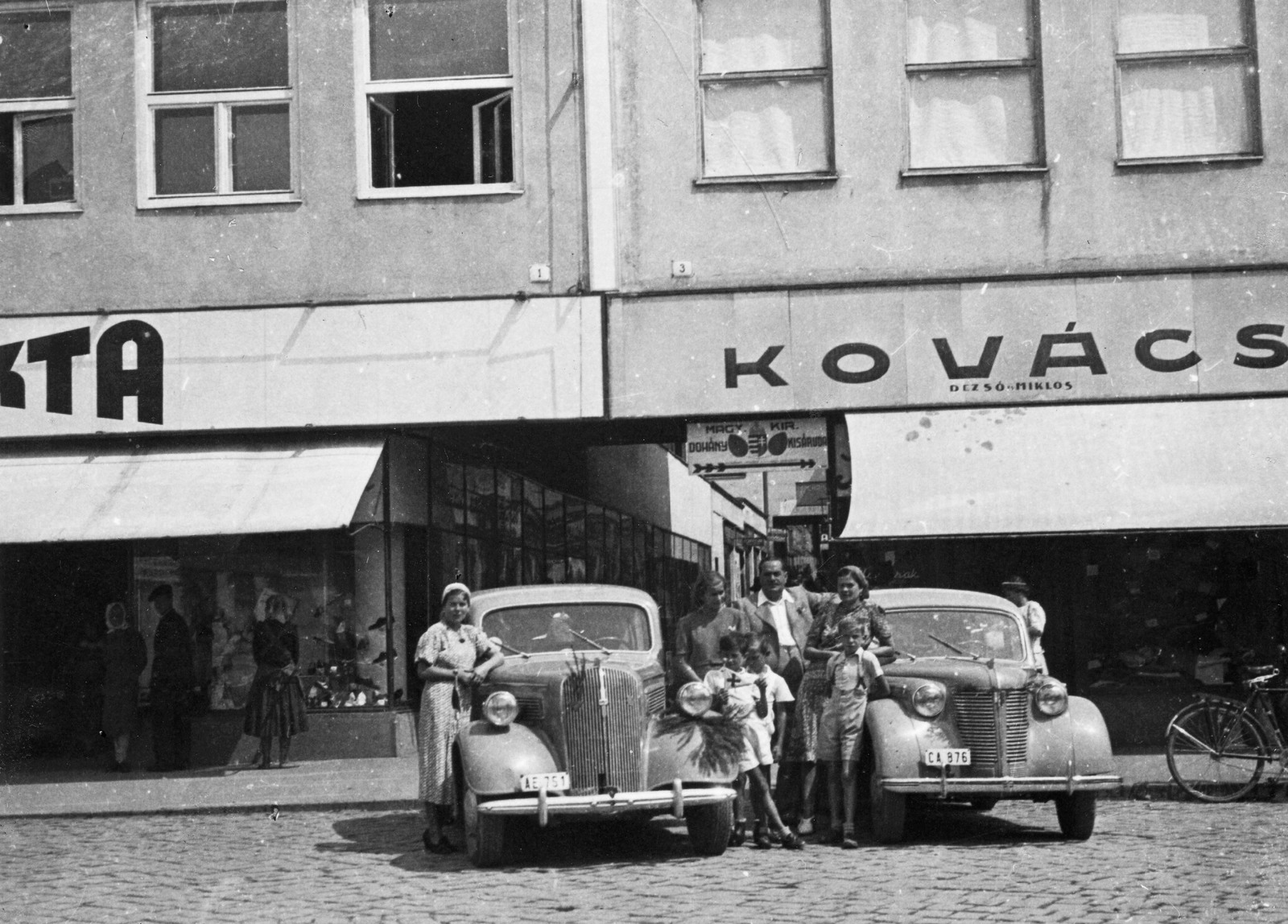 Ukraine,Zakarpattia Oblast, Uzhgorod, Fencik Eugén (ekkor Szurmay) tér 1. és 3., szemben a Színházi köz., 1939, Párdányi Miklós, sign-board, German brand, Opel-brand, tableau, tobacco shop, automobile, number plate, Fortepan #54930