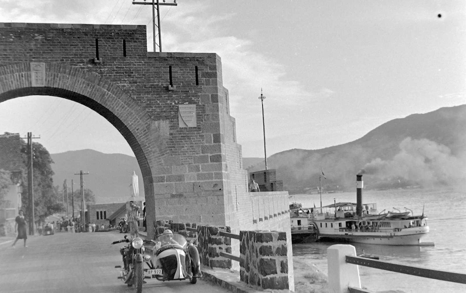 Hungary, Danube Bend, Visegrád, Vizibástya az országszászlóval és a Városkapu, háttérben IV. Béla szobra. A hajóállomáson a Tahi gőzhajó., 1939, Fortepan, ship, AJS-brand, motorcycle, sculpture, motorcycle with sidecar, steamboat, Tahi/MÁV III-ship, Béla IV of Hungary-portrayal, Fortepan #5602
