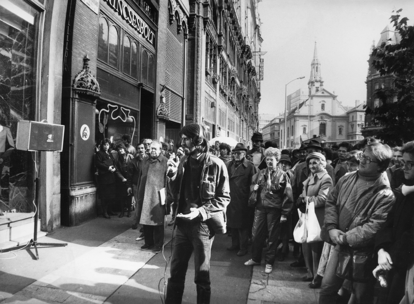 Hungary, Budapest V., Ferenciek tere (Felszabadulás tér) a Kígyó utca torkolatánál. A Magyar Rádió Napközben című műsorának riportere Rózsa Péter., 1980, Rádió és Televízió Újság, Szalay Zoltán, church, Show window, microphone, Baroque-style, Catholic Church, speaker, Budapest, Hungarian Radio, Franciscans, Fortepan #56206