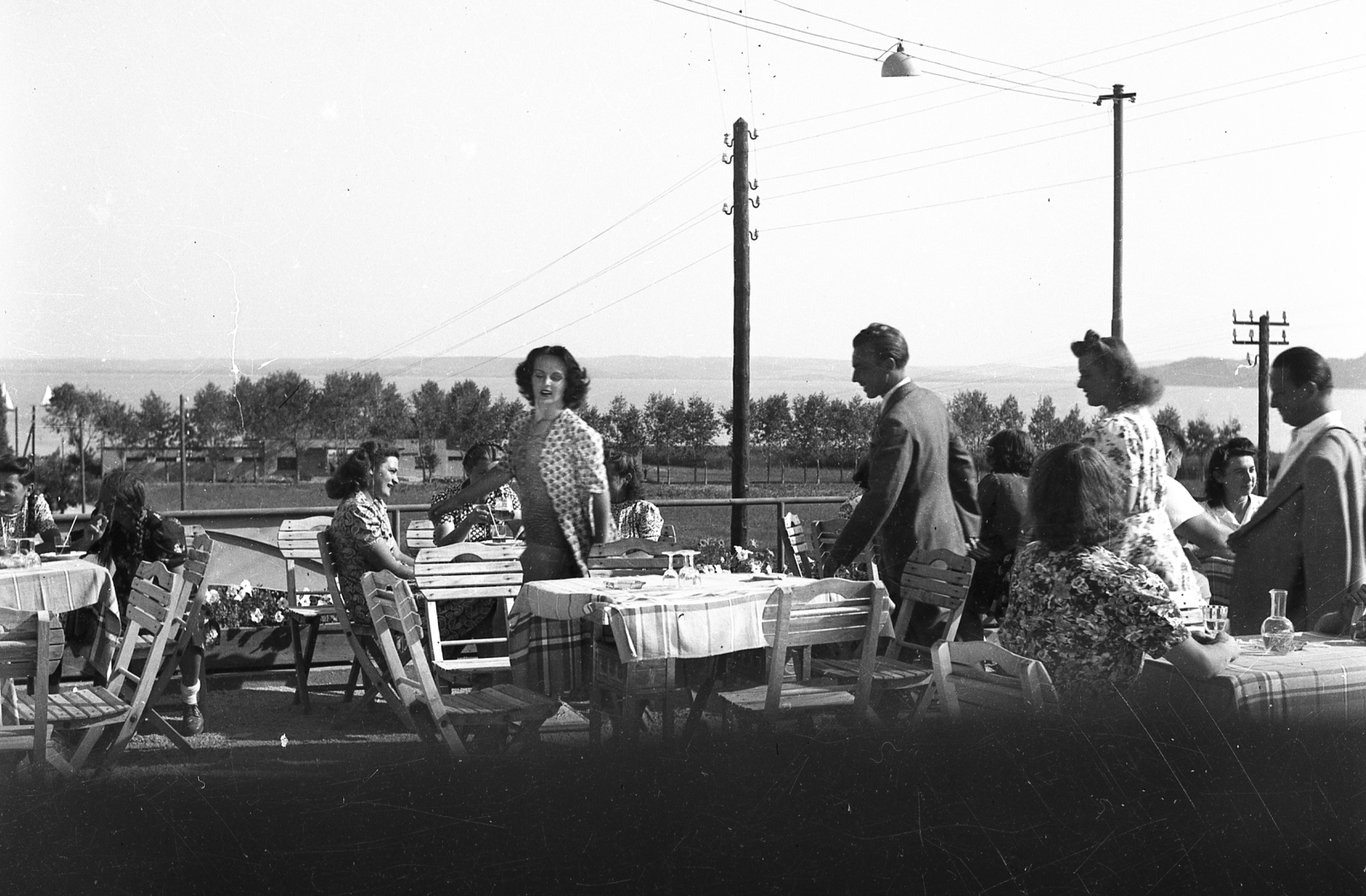 Hungary, Balatonfüred, Deák Ferenc (Csányi) utca, a Liliom étterem terasza. Háttérben az Esterházy strand. A középső asztalhoz tartó társaságban Naszódy Sándor és Pethes Ferenc színészek., 1940, Karabélyos Péter, hospitality, genre painting, view, companionship, garden furniture, Fortepan #57128