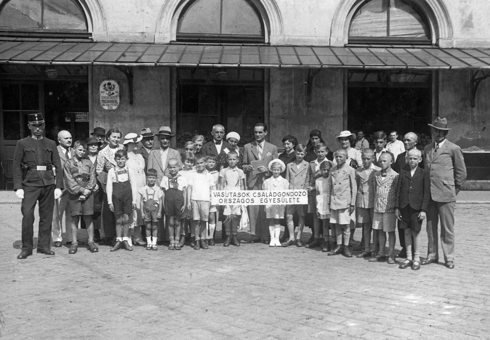 Hungary, Budapest VIII., Baross tér, postahivatal a Keleti pályaudvar épületében., 1931, Jurányi Attila, hat, tableau, women, men, cop, kids, crest, post, railroader, Budapest, Fortepan #58259