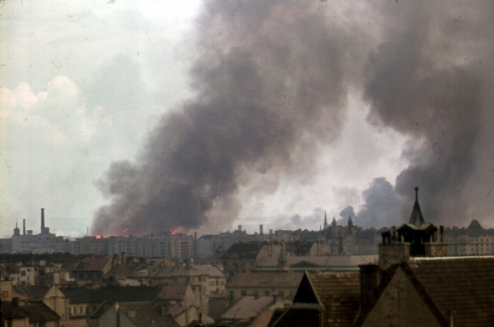 Magyarország, Budapest I.,Budapest XIII., vízivárosi háztetők, kilátás a Fiáth János utca irányából Újlipótváros felé, háttérben a lángoló Angyalföld az ipartelep szőnyegbombázása után., 1944, Fortepan, színes, háborús kár, második világháború, látkép, füst, torony, Budapest, Fortepan #5842