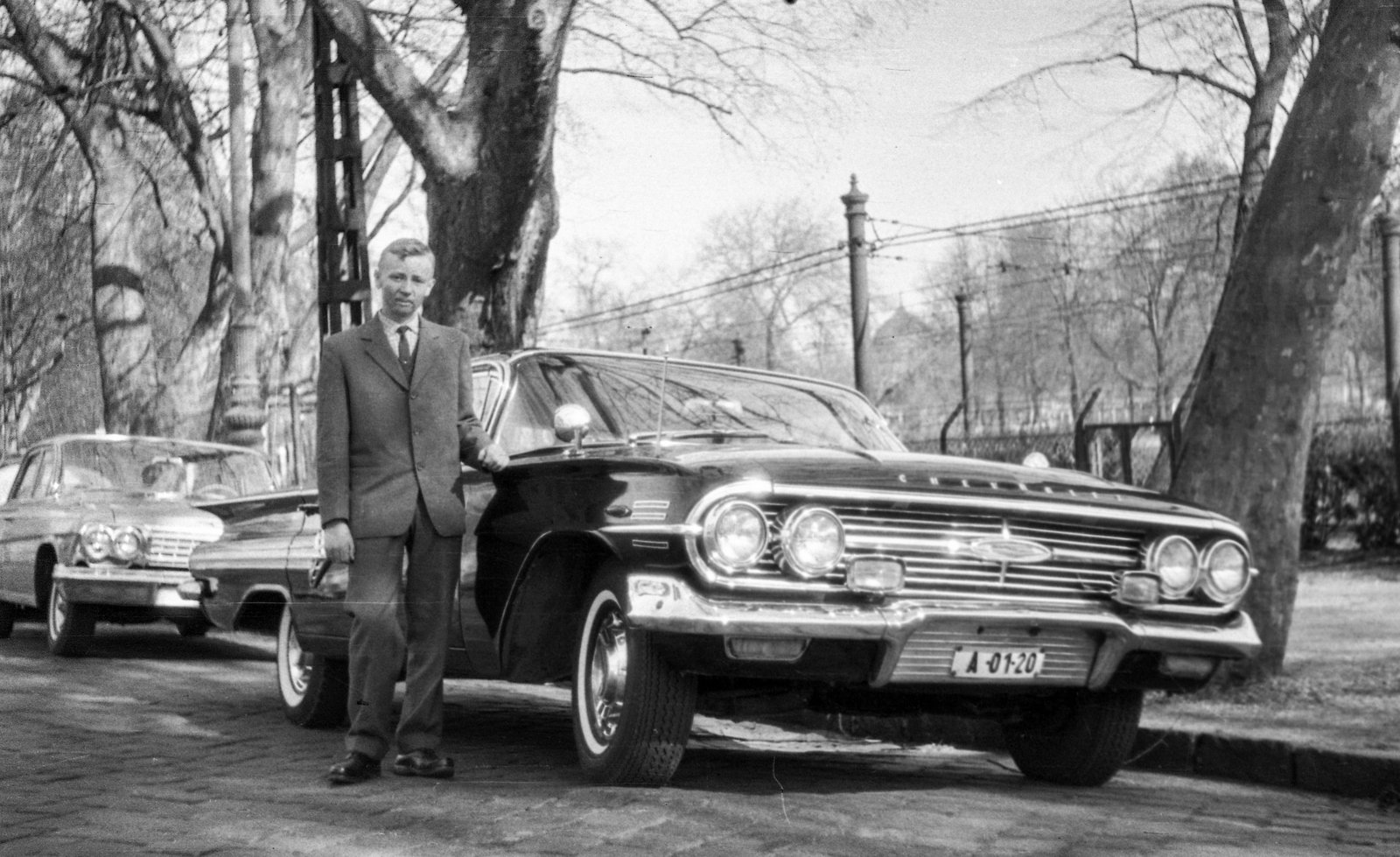 Hungary, Budapest XIV., Állatkerti körút. 1960-as Chevrolet Impala az Állatkert előtt (miniszteri rendszámmal), háttérben a Millenniumi Földalatti Vasút mára megszűnt felszíni szakasza és a Széchenyi fürdő kupolája., 1966, Braun Antal, american brand, man, Chevrolet-brand, automobile, number plate, Budapest, Fortepan #59491