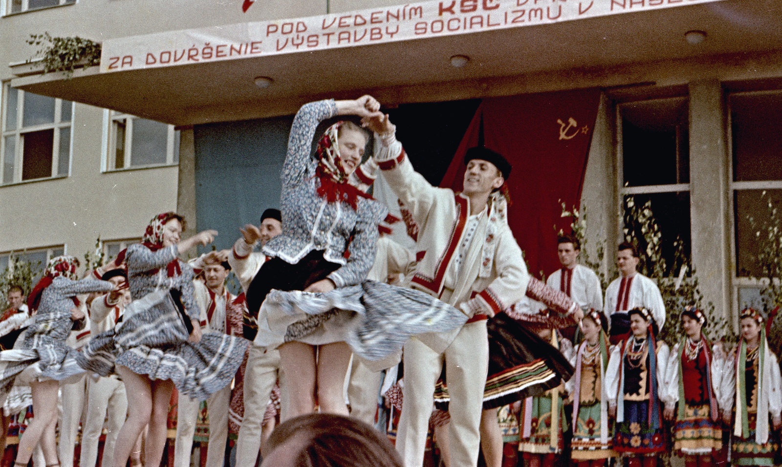 Slovakia, Poltár, népi táncosok az iskola előtt., 1958, Zsanda Zsolt, Vajszada Károly, Czechoslovakia, colorful, flag, dance, political decoration, folk costume, slogan, Fortepan #60226