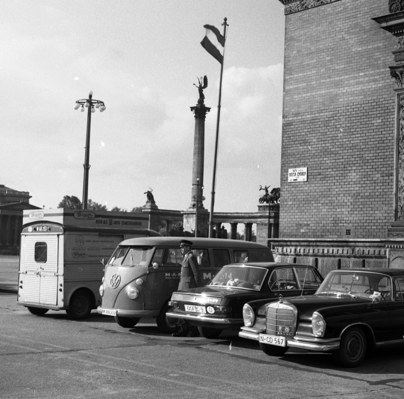 Hungary, Budapest XIV., Dózsa György út a Műcsarnok épületének sarkánál, háttérben a Hősök tere., 1967, Magyar Rendőr, Mercedes-brand, Volkswagen-brand, minivan, number plate, street name sign, pillar, flag pole, Budapest, country code sign, Archangel Gabriel-portrayal, Fortepan #65519