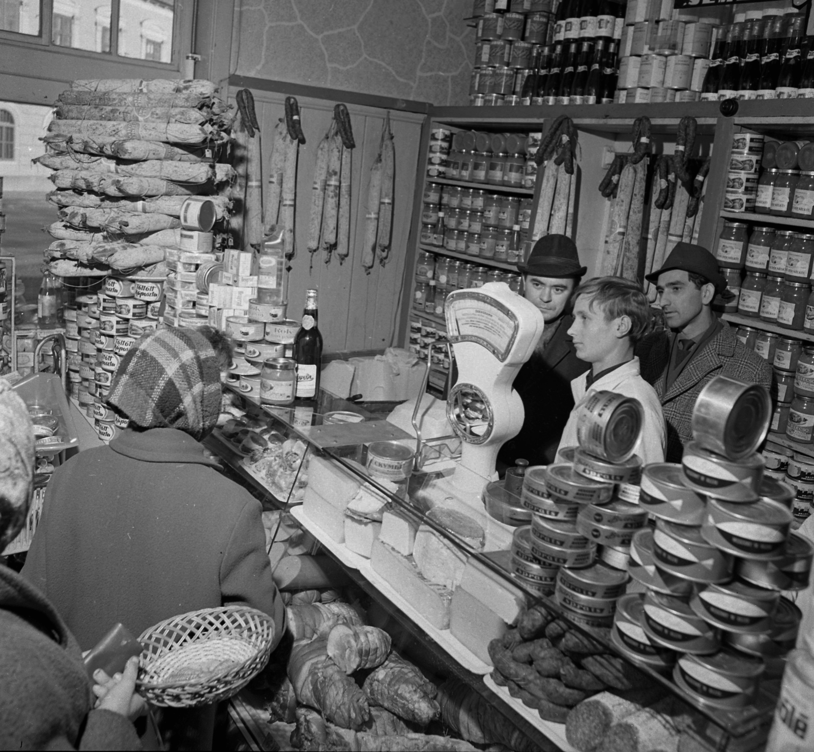 Hungary, Hatvan, társadalmi ellenőrök az Erzsébet (Lenin) tér 12-14. szám alatti élelmiszerboltban. A kirakaton keresztül az 1-es számú ház látszik., 1968, Magyar Rendőr, hat, sausage, basket, headscarf, coat, tin can, counter, ham, salami, cheese, cloak, grocery store, wallet, scale, fat, Fortepan #65764