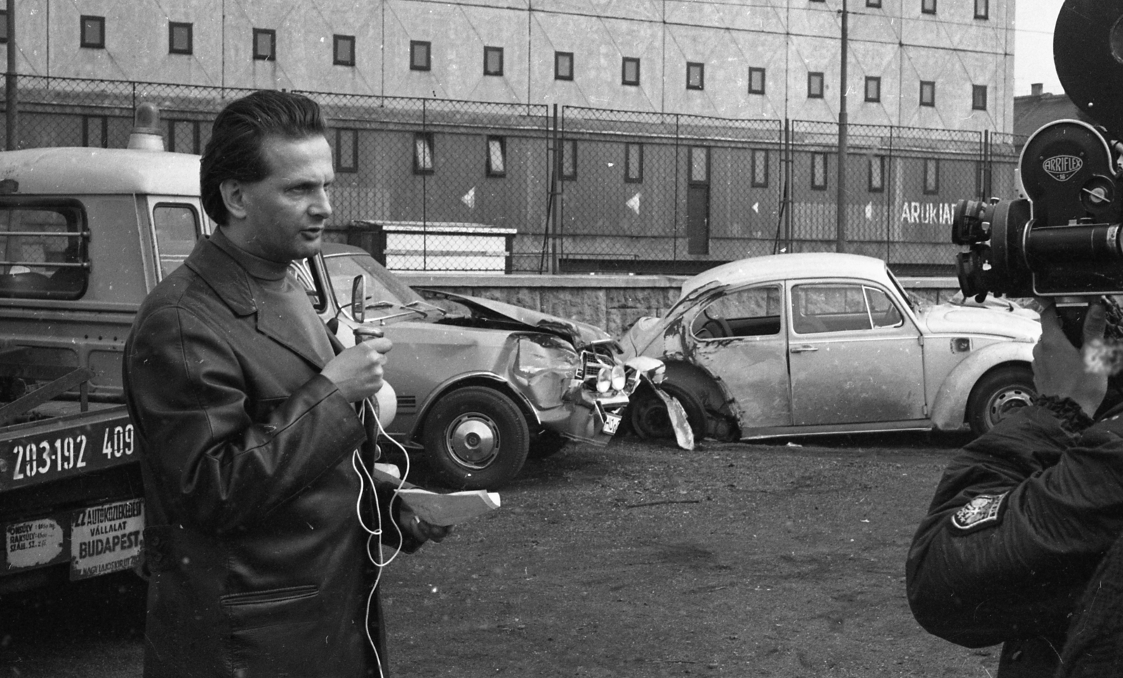 Hungary, Budapest XIII., Tomori utca, a Magyar Televízió Mindenki közlekedik... című műsorának felvétele az Autóközlekedési Vállalat (AKÖV) Madarász Viktor utcai, 22. számú üzemegysége mellett. A mikrofonnál Petress István műsorvezető, háttérben a Tomori utca 33., a Műszer- és Iradagépértékesítő Vállalat (MIGÉRT) raktára., 1971, Magyar Rendőr, Barkas-brand, Volkswagen-brand, wreck, movie camera, Volkswagen Beetle, Budapest, Fortepan #65821