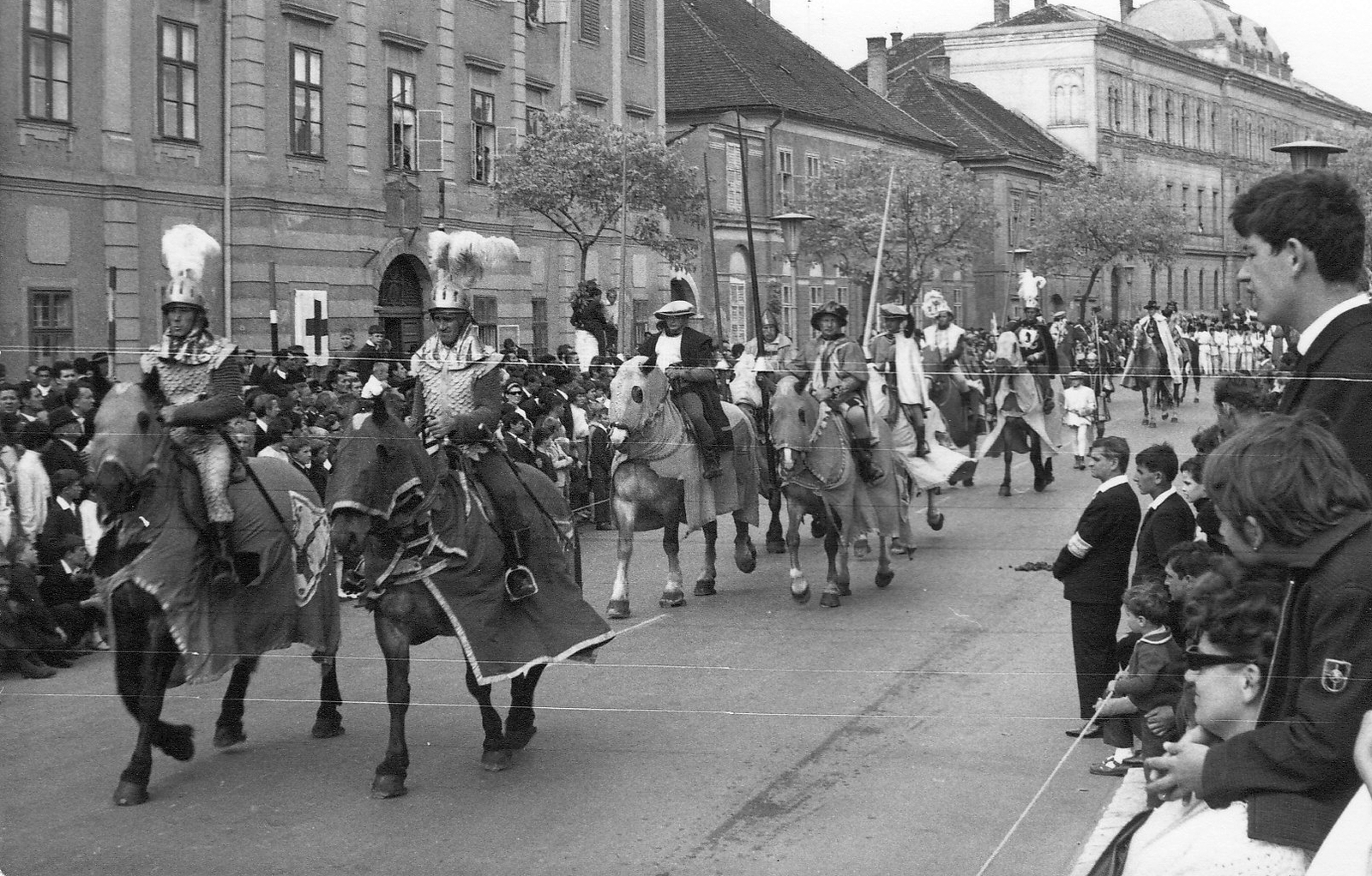 Hungary, Szombathely, Szily János (Alkotmány) utca, a Savaria Történelmi Karnevál résztvevőinek felvonulása a Mindszenty József (Templom) tér közelében. Háttérben balra a Savaria Gimnázium és Középiskolai Leánykollégium (később Egyházmegyei Könyvtár és a Brenner János Kollégium) épülete, jobbra a Szombathelyi Törvényszék épülete., 1967, Kelemen Zoltán, street view, march, costume, audience, rider, Fortepan #69948