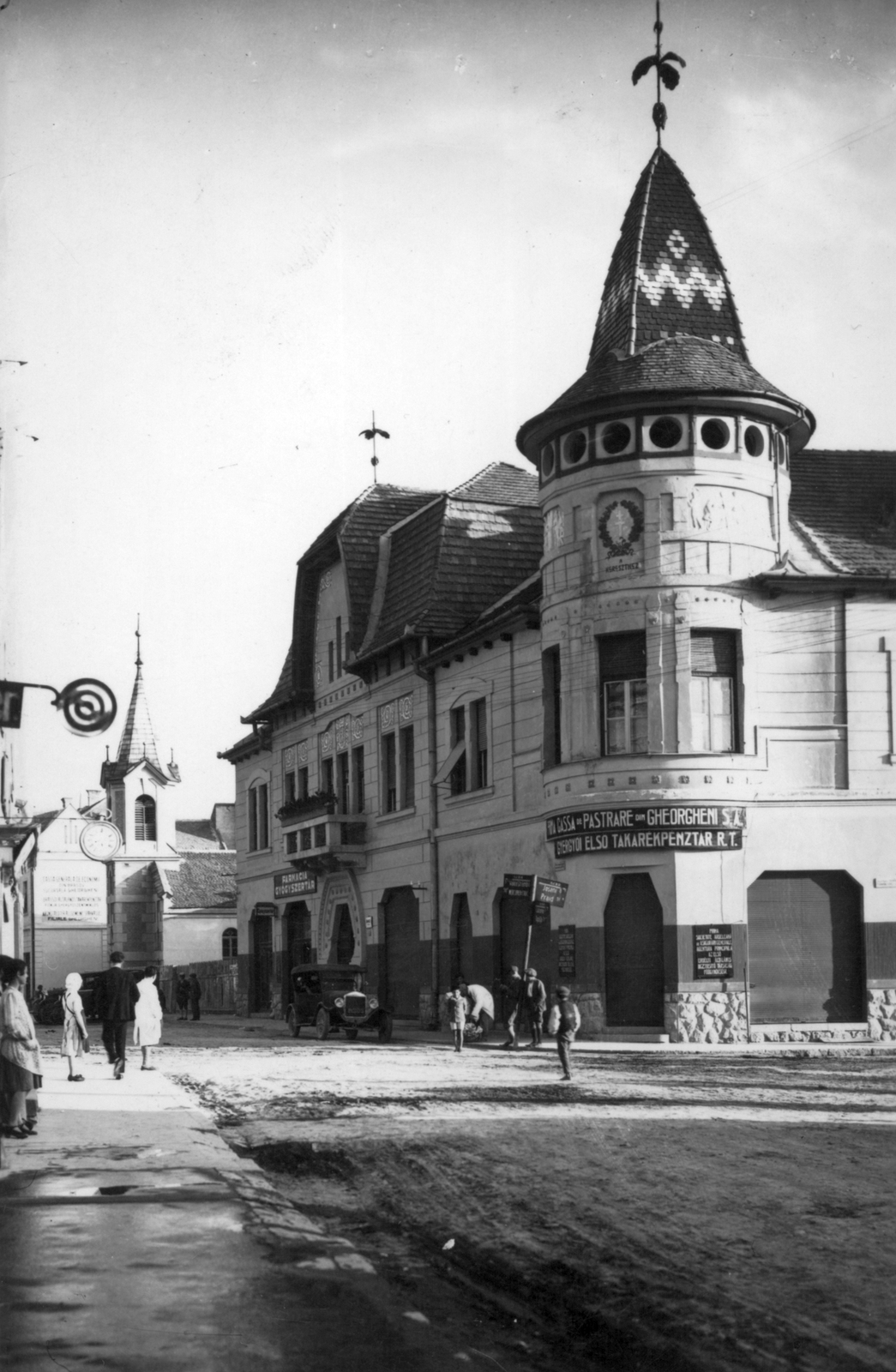 Románia,Erdély, Gyergyószentmiklós, Kárpát utca, jobbra a Kossuth Lajos utca (Vasút utca) torkolata, szemben a Szabadság téren (Piata Libertatii, ekkor Kossuth Lajos tér), a Városháza és a református templom., 1935, Jáki László, gyógyszertár, automobil, Takarékpénztár, cégér, Fortepan #70355
