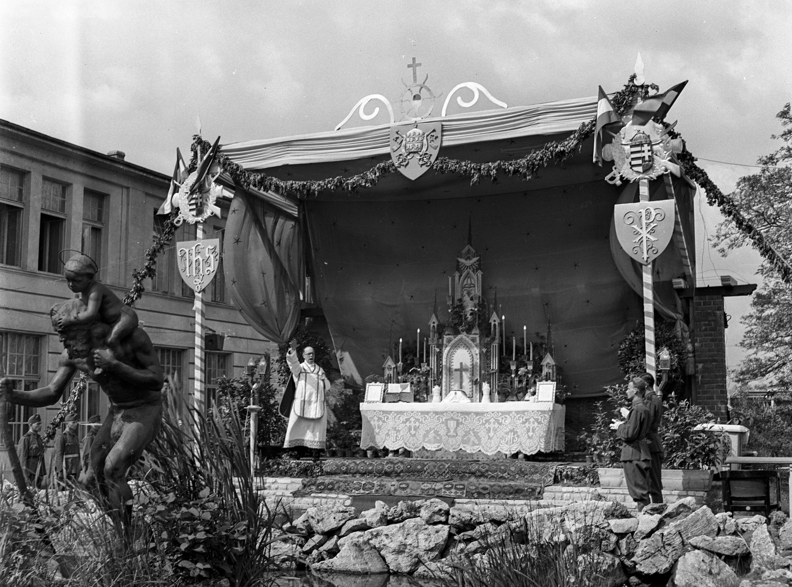 Magyarország, Budapest XVI., Mátyásföld, Újszász utca 41-43. (Keresztúri út 1-3.), a Magyar Királyi Honvéd gépkocsiszertár díszudvara, az ünnepi mise oltára. Előtérben Szent Kristóf szobra (Hűvös László, 1910.)., 1943, Lissák Tivadar, szobor, oltár, liturgia, Budapest, Szent Kristóf-ábrázolás, nyakban ülés, Fortepan #72099