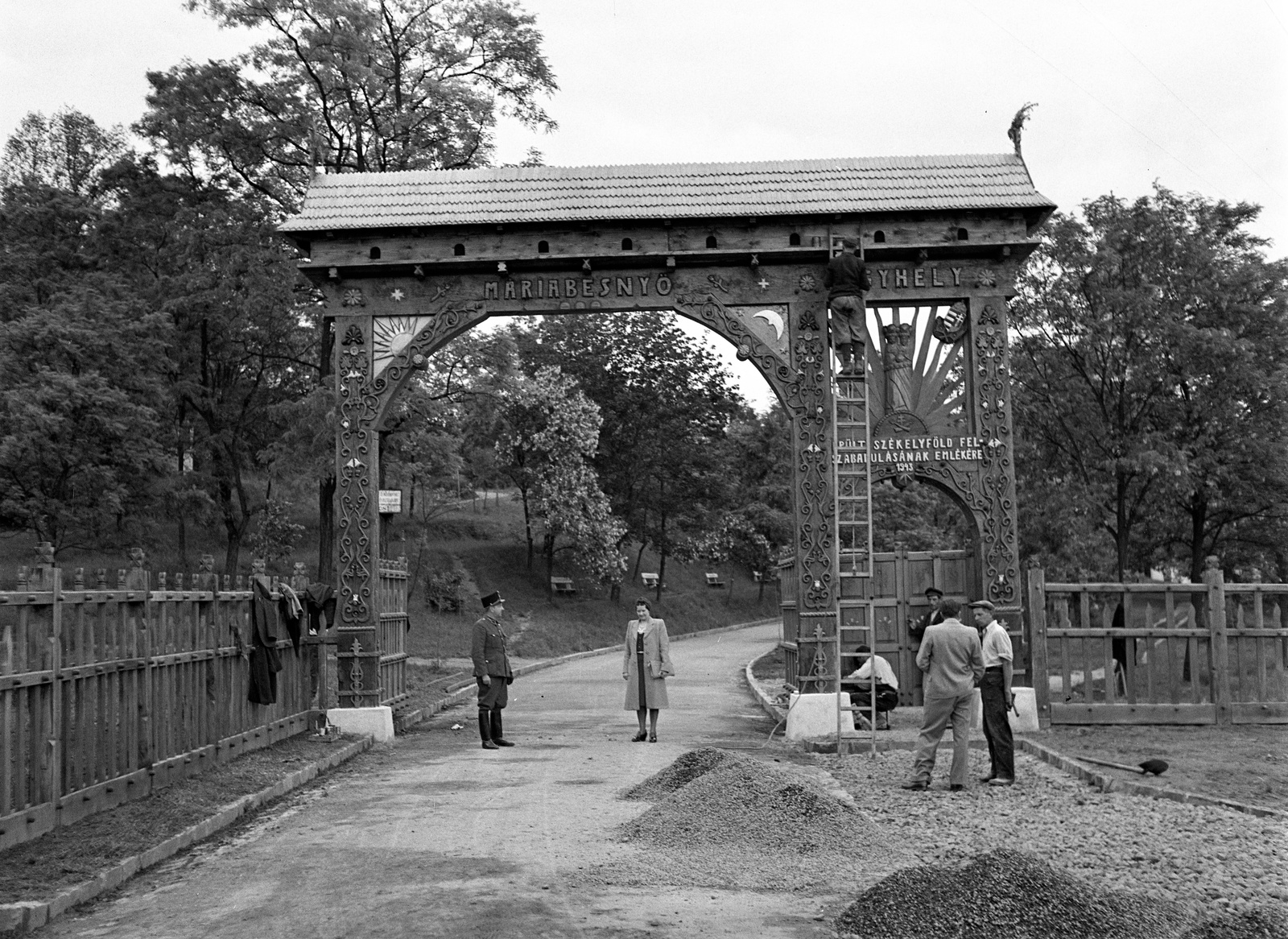 Magyarország, Máriabesnyő, Gödöllő, székely kapu a kegyhelyhez vezető úton., 1943, Lissák Tivadar, egyenruha, felirat, építkezés, polgárság, létra, kerítés, nő, fedeles kapu, fafaragás, katolikus, zarándokhely, Fortepan #72141