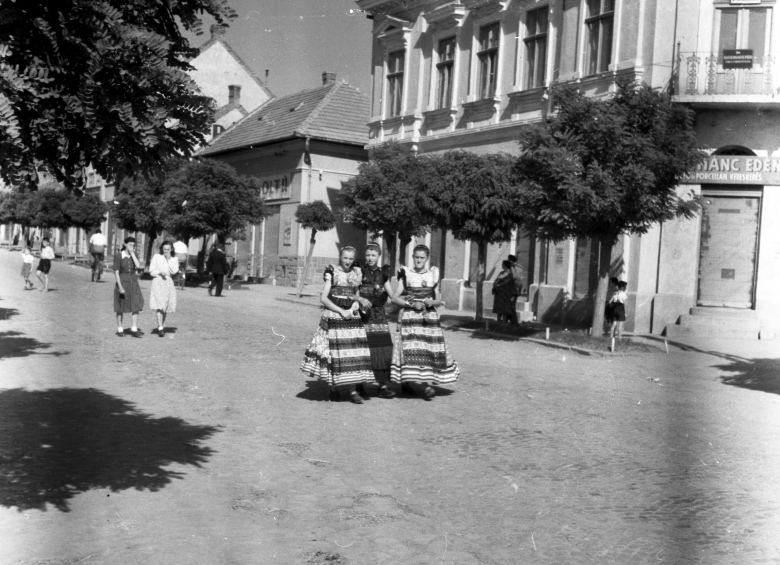 Magyarország, Mezőkövesd, Mátyás király út a Mátyás utcánál, háttérben a Tulipán utca torkolata. Lányok matyó népviseletben., 1948, Lissák Tivadar, cégtábla, nők, utcakép, népviselet, Matyó népviselet, Fortepan #73059