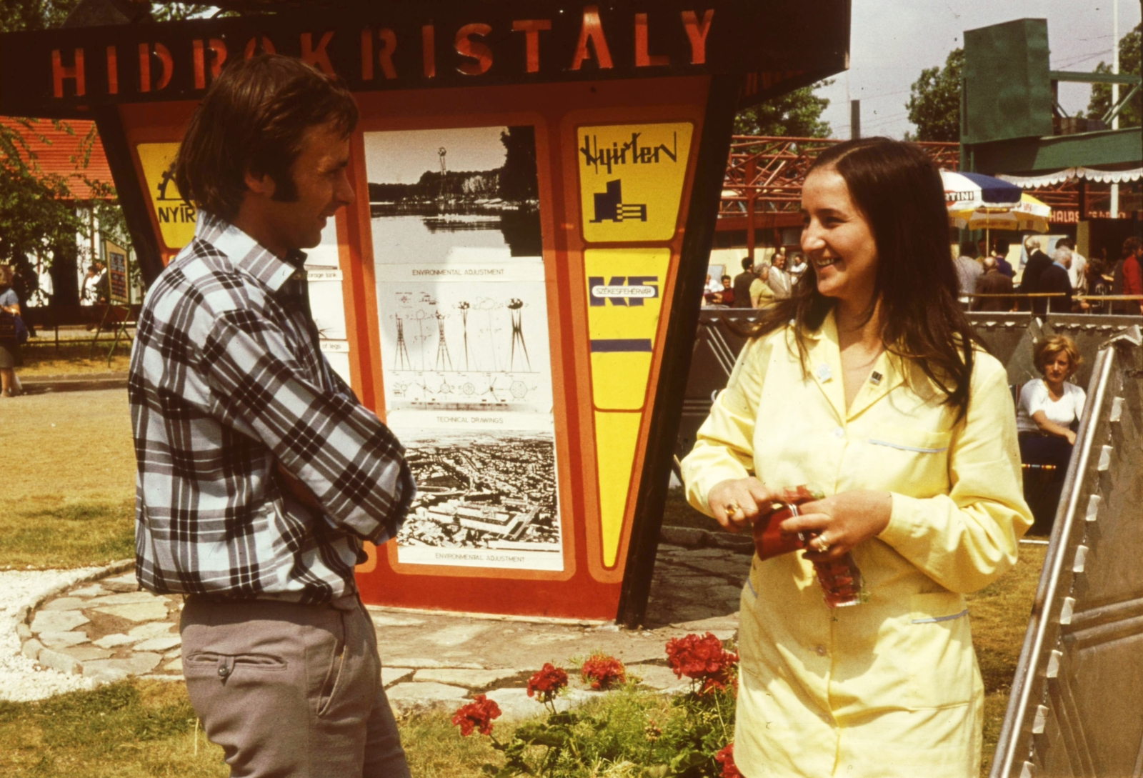 Hungary, Budapest X., Albertirsai úti vásárterület., 1973, Fülöp Imre, Kalocsai István, colorful, smile, ad pillar, technical drawing, man, badge, woman, overall, Budapest, talks, plaid shirt, arms crossed over the chest, untitled, Fortepan #74739