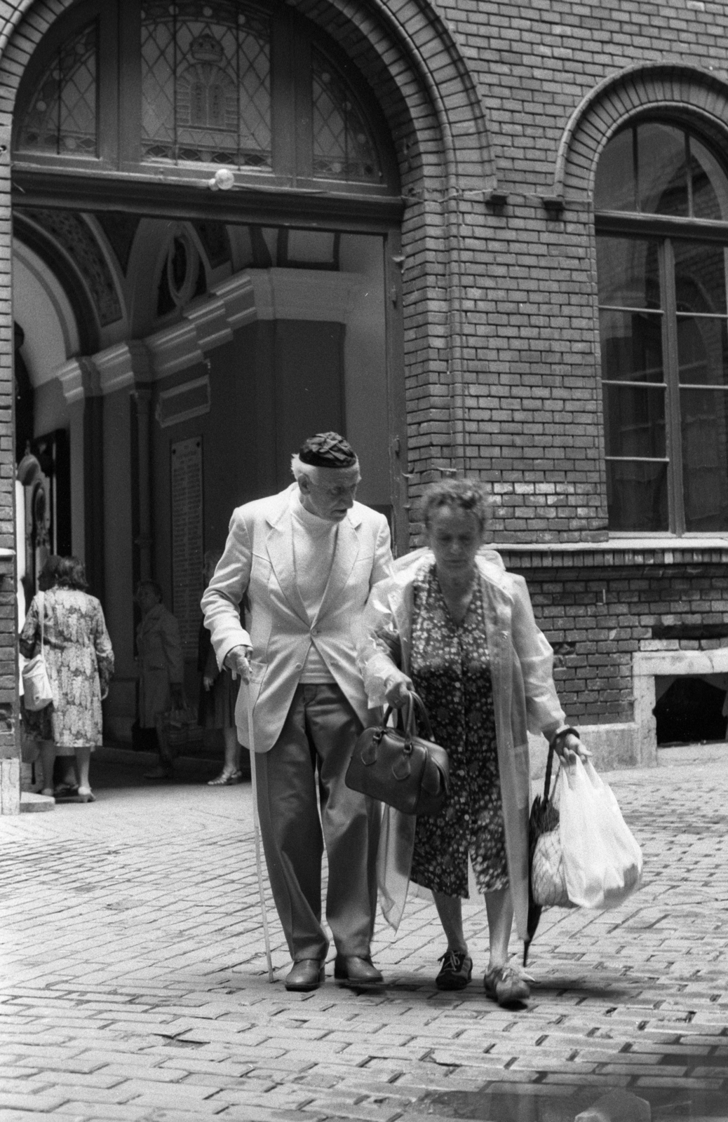 Magyarország, Budapest VII., Síp utca 12., a Budapesti Zsidó Hitközség székház udvara., 1990, Erdei Katalin, esernyő, cekker, esőkabát, kézitáska, idős ember, keramit, zsidóság, Budapest, kipa, Fortepan #76263