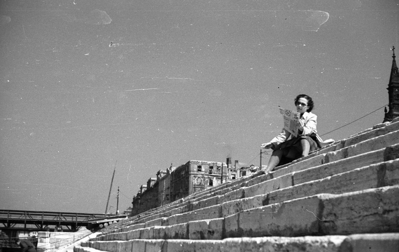 Hungary, Budapest V., pesti alsó rakpart a Petőfi térnél, balra a Petőfi (Böske) pontonhíd., 1947, Berkó Pál, pontoon bridge, Budapest, sitting on stairs, reading, newspaper, lady, smoking, Fortepan #78577