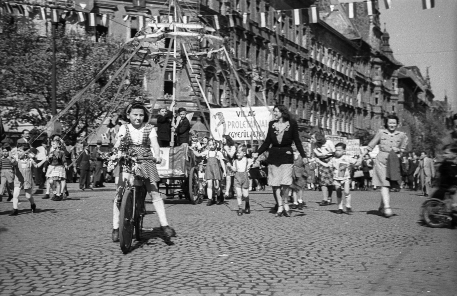 Magyarország, Budapest VI., Oktogon, május 1-i ünnepség felvonulói. Szemben a Teréz körút., 1946, Berkó Pál, Budapest, hölgy, gyerekek, kislány, kerékpár, transzparens, kézenfogva, májusfa, Fortepan #78629