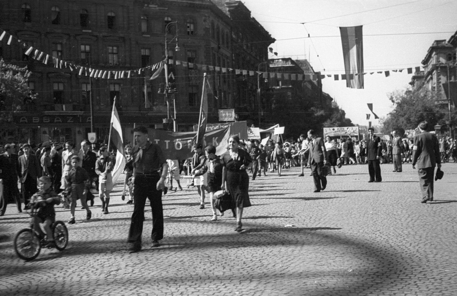 Magyarország, Budapest VI., Oktogon, május 1-i ünnepség felvonulói. Szemben az Andrássy út a Jókai tér felé nézve., 1946, Berkó Pál, kerékpár, úttörő, zászló, utcakép, életkép, felvonulás, kockakő, transzparens, Budapest, Fortepan #78636