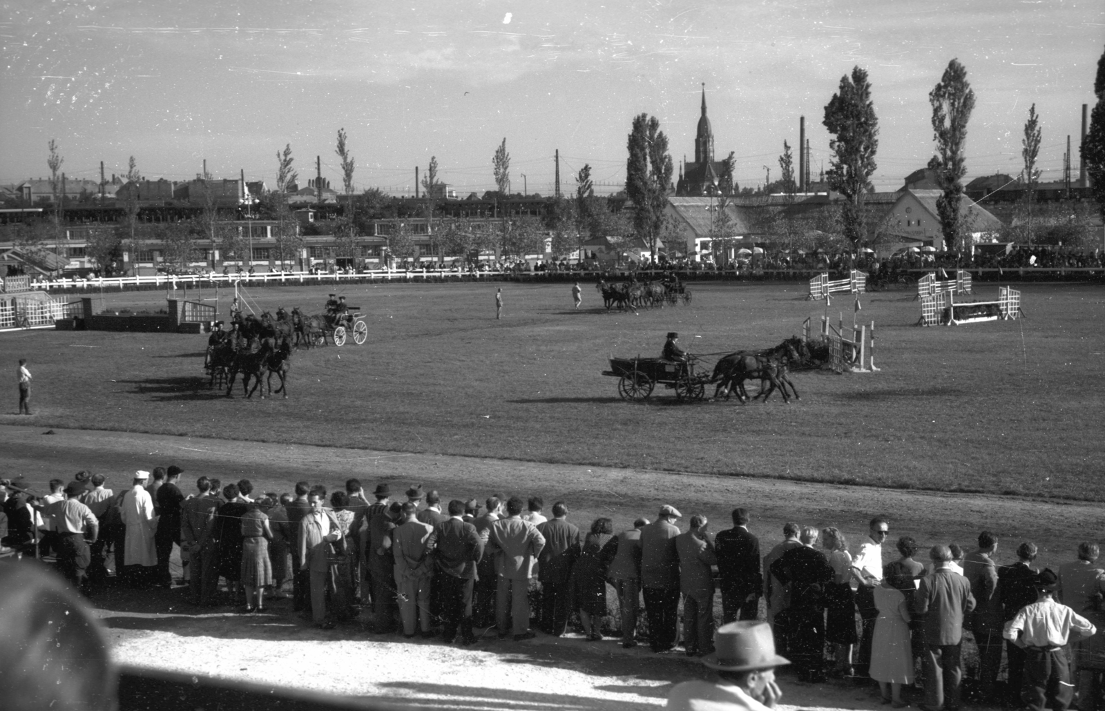 Hungary, Budapest X., Albertirsai út, Mezőgazdasági kiállítás lovaspályája. Háttérben a kőbányai Szent László-templom., 1948, Berkó Pál, carriage, chariot, coach, audience, pitch, equestrian sports, Budapest, Fortepan #79110