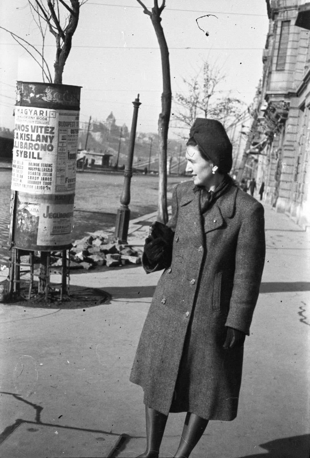 Magyarország, Budapest V., Belgrád (Ferenc József) rakpart, háttérben a lerombolt Erzsébet híd., 1946, Berkó Pál, Budapest, hölgy, kalap, retikül, hirdetőoszlop, Fortepan #79544