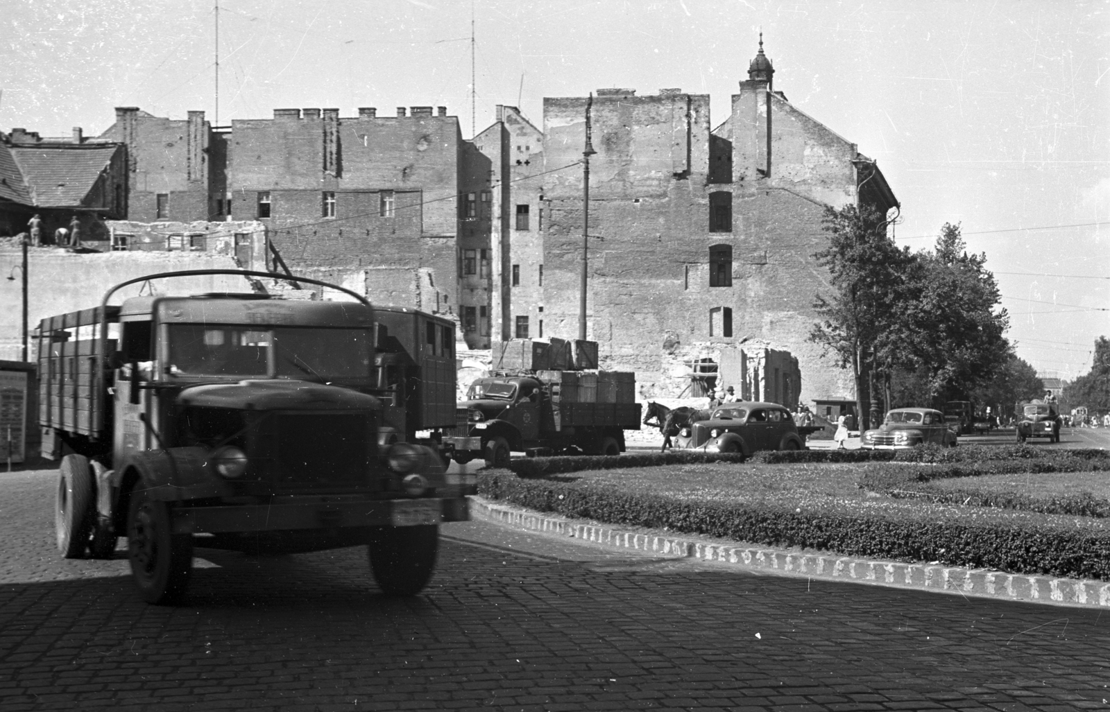 Magyarország, Budapest V., Deák Ferenc tér. Háttérben a lebontott Kemnitzer ("Két török") ház helye., 1954, UVATERV, forgalom, lovaskocsi, teherautó, utcakép, városkép, Csepel-márka, fogat, rom, tűzfal, lámpaoszlop, automobil, Csepel B-350/D-350, körforgalom, Budapest, Chevrolet-márka, Fortepan #79949