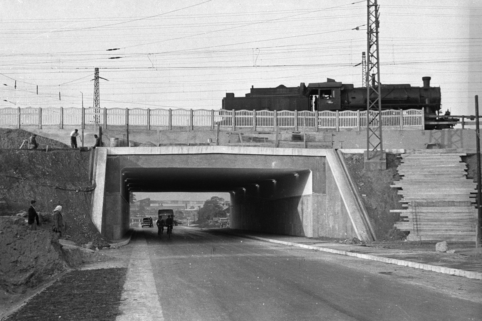 Hungary, Tata-Tóváros, 1-es főút, a Budapest-Hegyeshalom vasútvonal (később iparvágányok) felüljárója Mésztelep felé nézve., 1961, UVATERV, bicycle, steam locomotive, bridge, construction, underpass, fence, road construction, M21 Wolga, MÁV Class 411, catenary wire, Fortepan #80163