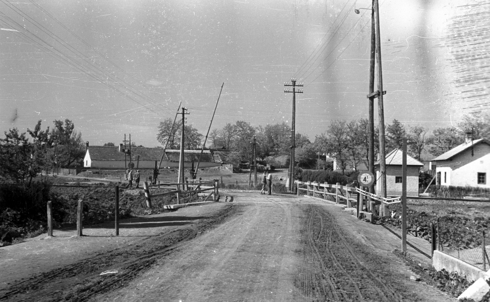 Hungary, Vértesacsa, Fő utca a katolikus templomtól a vasúti átjáró felé nézve., 1951, UVATERV, village, bridge, street view, barrier, dirt road, pylon, Fortepan #80177