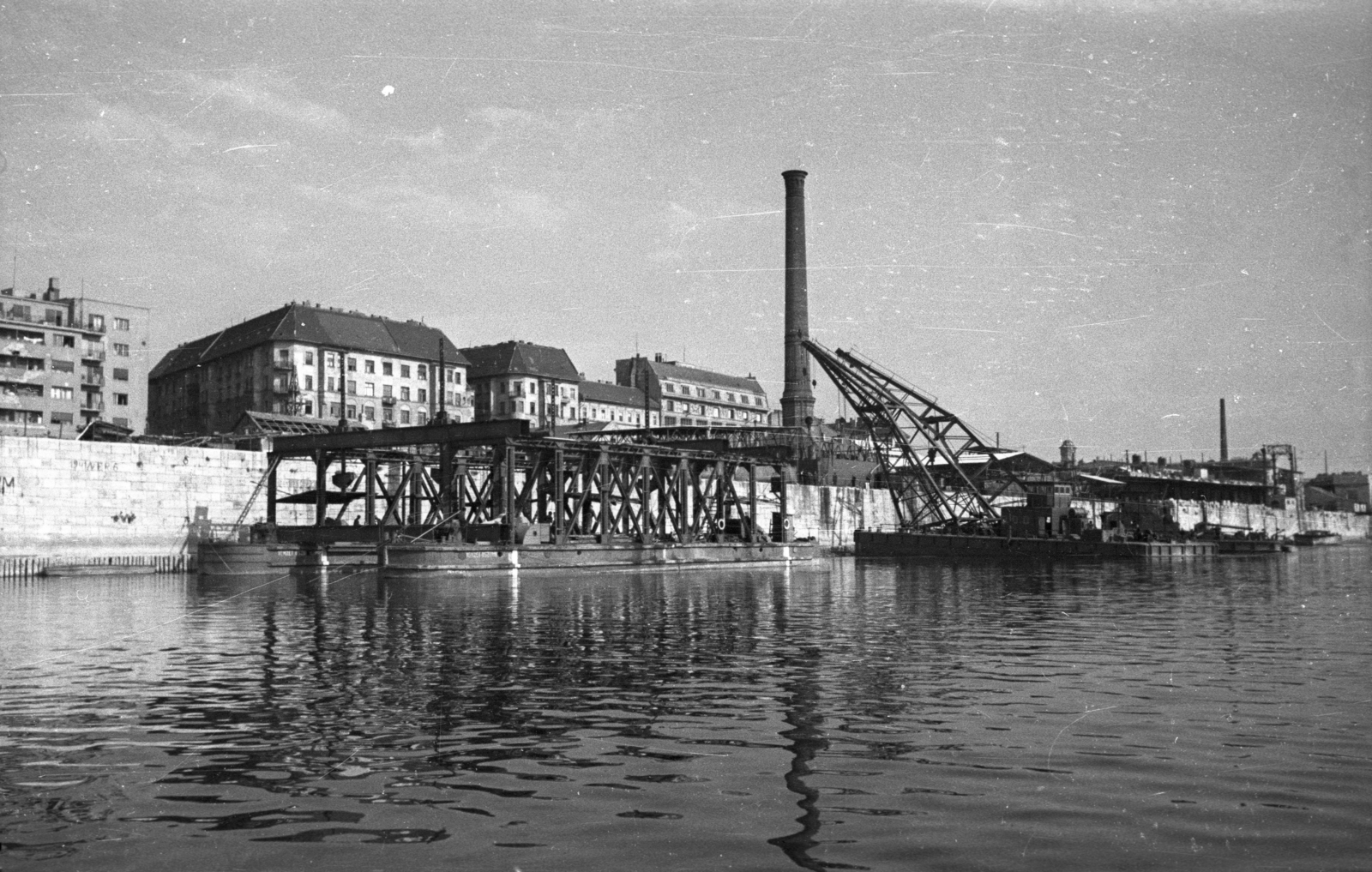 Hungary, Budapest IX., az Elevátor-ház kéménye és a Közraktár utca házai a Dunáról nézve. Előtérben a Petőfi híd újjáépítéséhez használt dereglye és a hídelemek beemelését végző úszódaruk., 1951, UVATERV, chimney, dredge, Budapest, Fortepan #80256