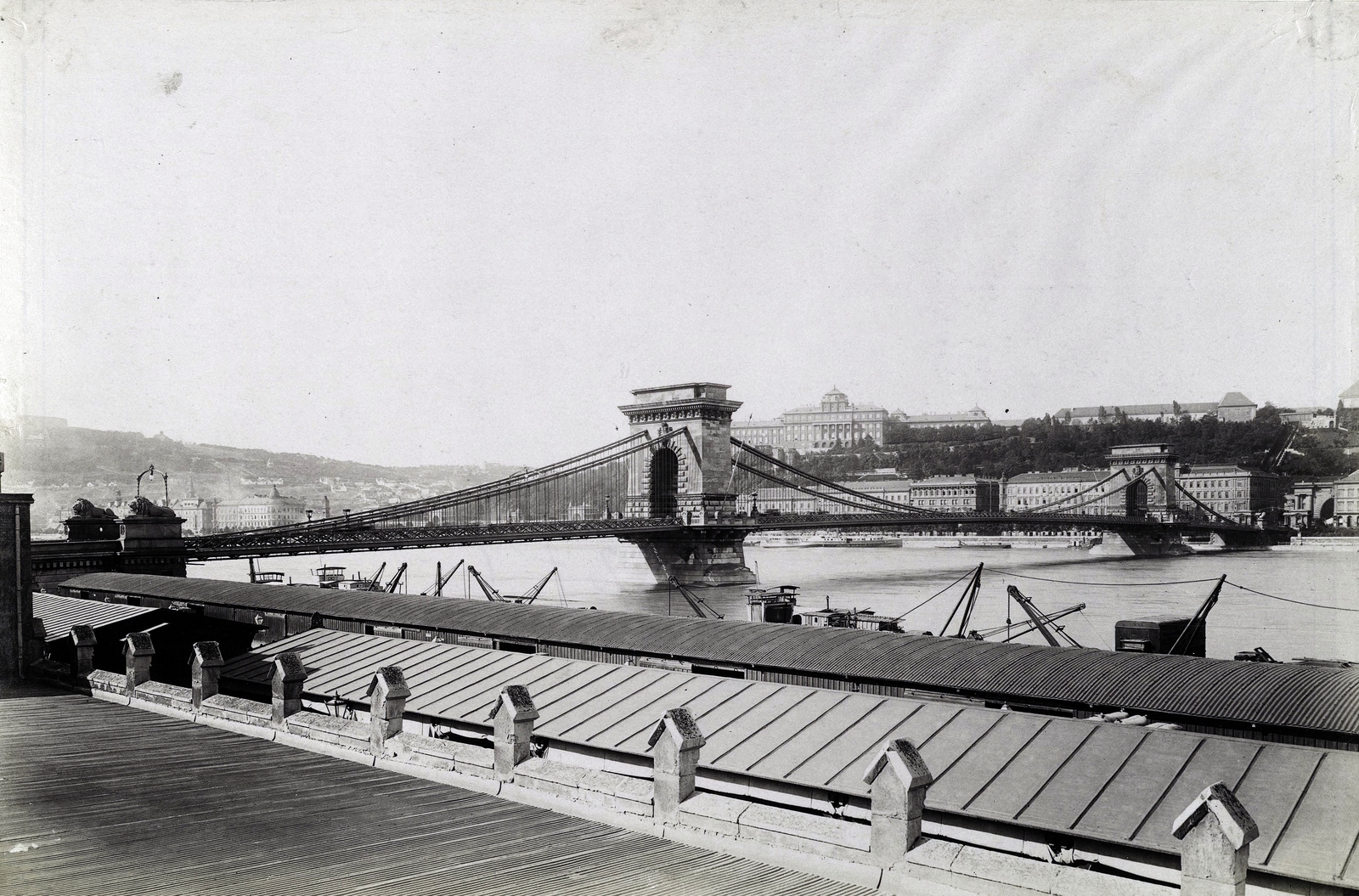 Hungary, Budapest V., pesti alsó (Rudolf) rakpart, teherhajó kikötő raktárai. Szemben a Széchenyi Lánchíd, háttérben a Királyi Palota (később Budavári Palota). A felvétel 1896 körül készült. A kép forrását kérjük így adja meg: Fortepan / Budapest Főváros Levéltára. Levéltári jelzet: HU.BFL.XV.19.d.1.08.078, 1900, Budapest Főváros Levéltára / Klösz György fényképei, Klösz György, Budapest, suspension bridge, William Tierney Clark-design, Fortepan #82603