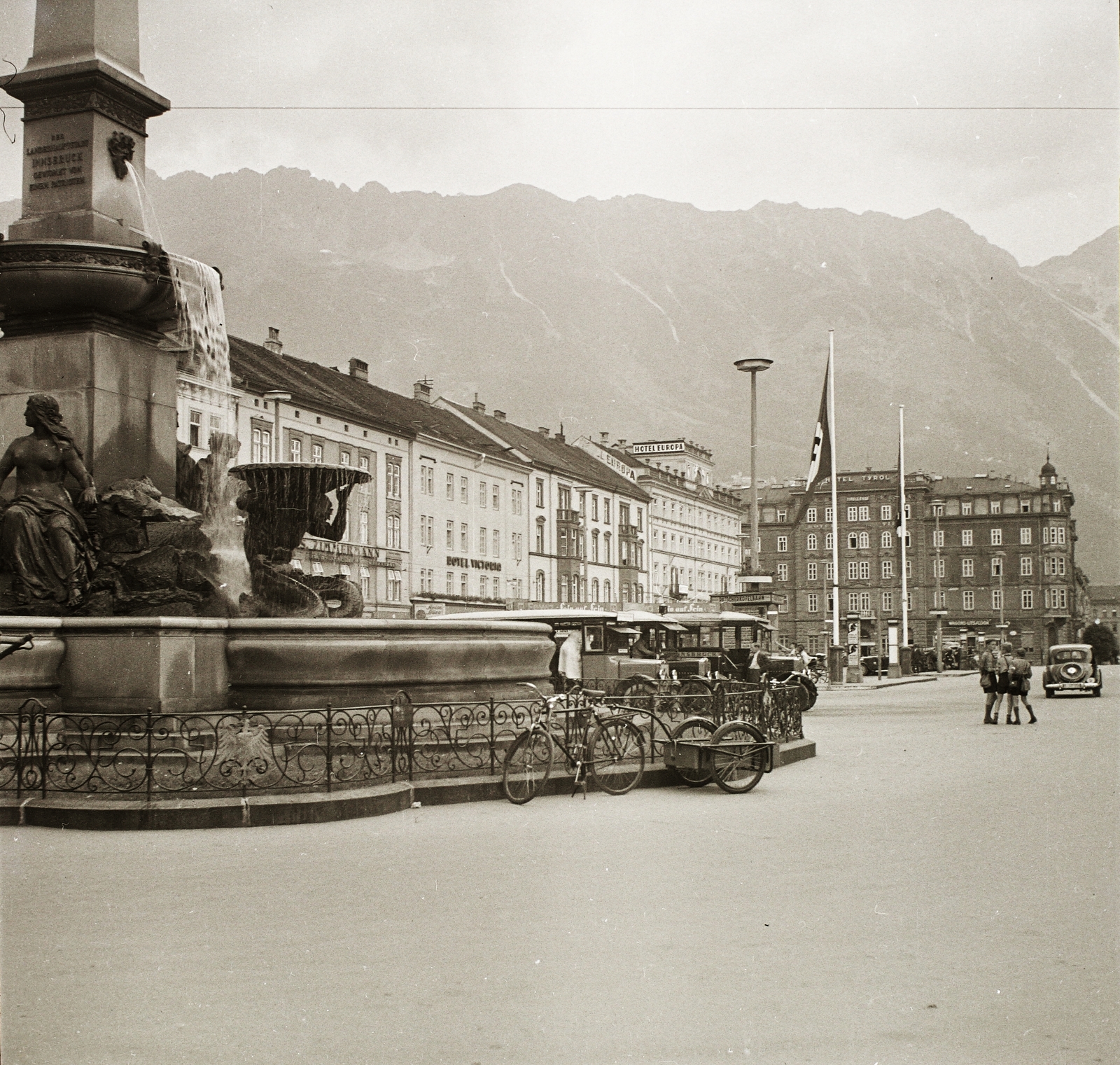 Austria, Innsbruck, Südtiroler Platz, Vereinigungsbrunnen (1940-ben lebontották)., 1939, Ebner, bicycle, fountain, bus, flag, swastica, automobile, flag pole, Atlas-portrayal, Fortepan #83874